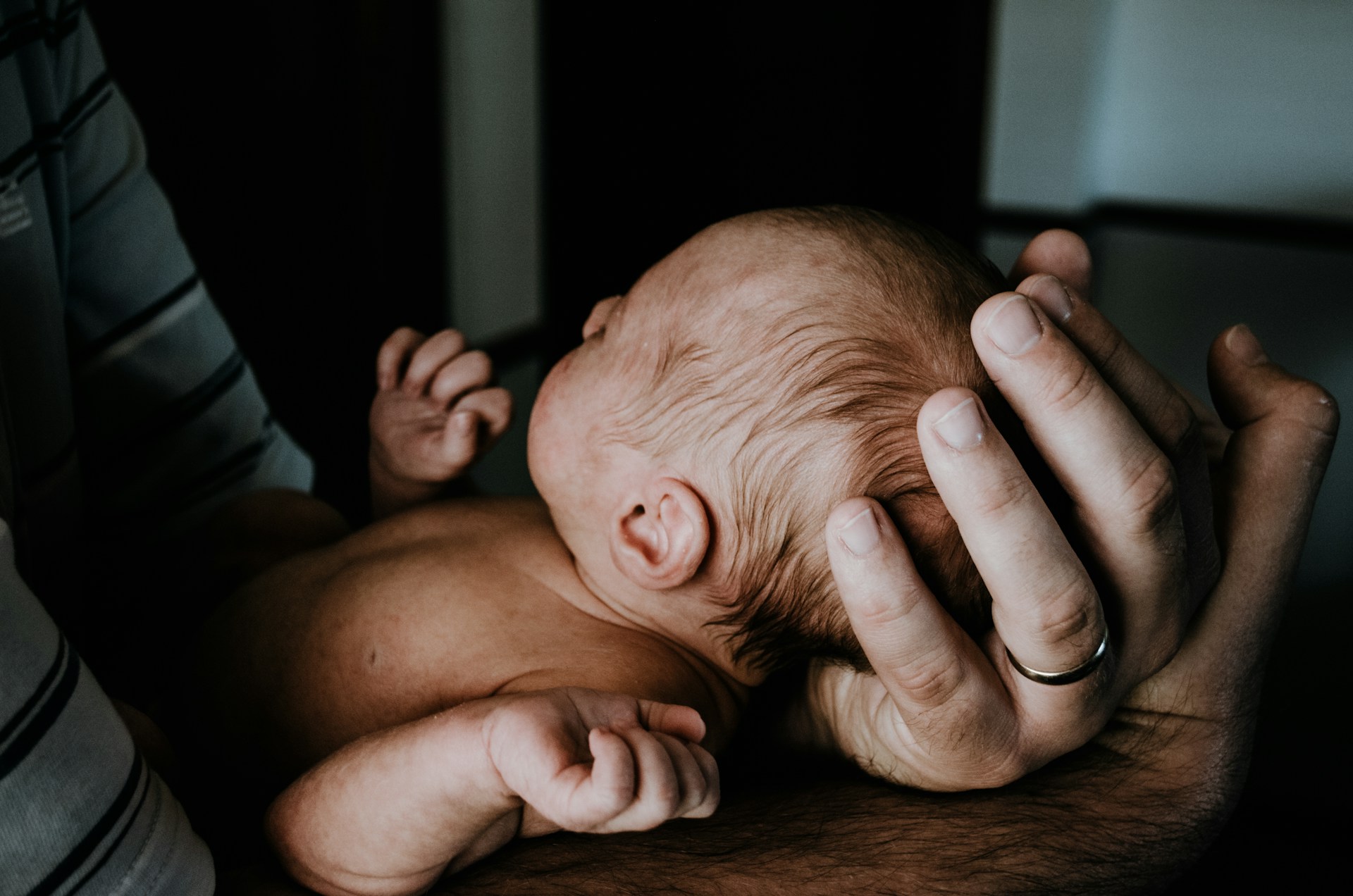 Un homme submergé par l'émotion tient un nouveau-né dans ses bras | Source : Unsplash