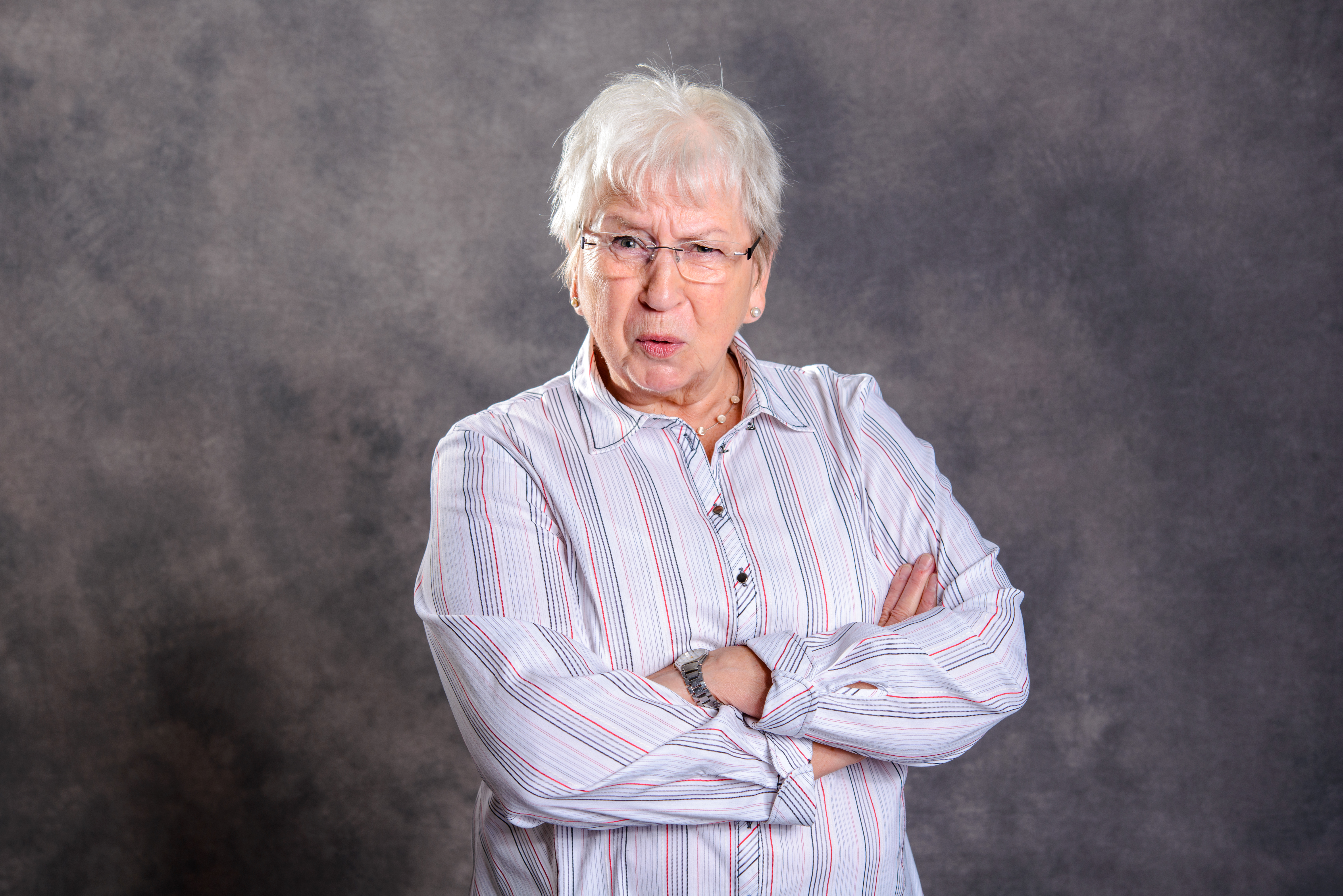 Une femme âgée bouleversée, les bras croisés contre sa poitrine | Source : Shutterstock