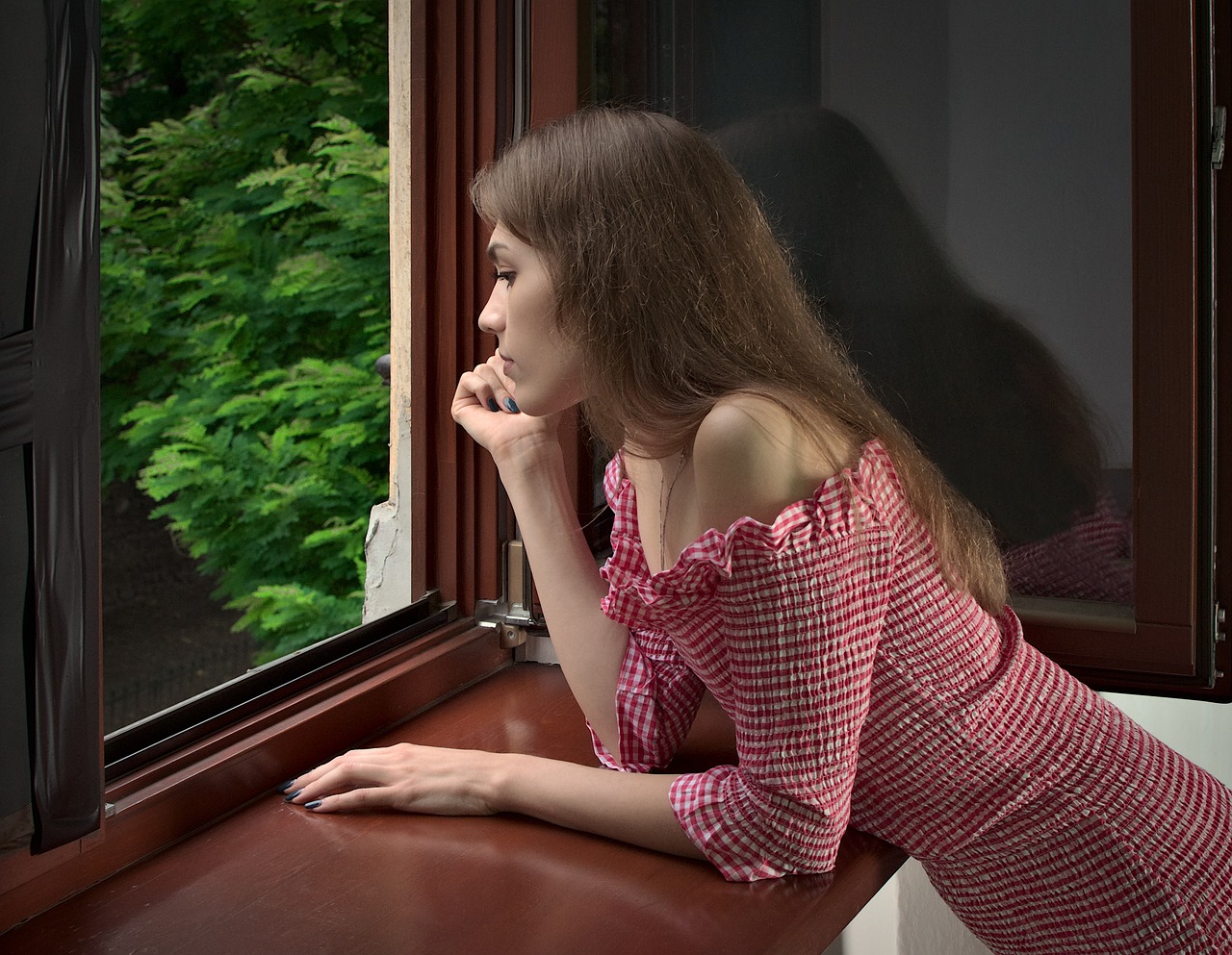 Jeune femme accoudée à la fenêtre | Source : Pixabay