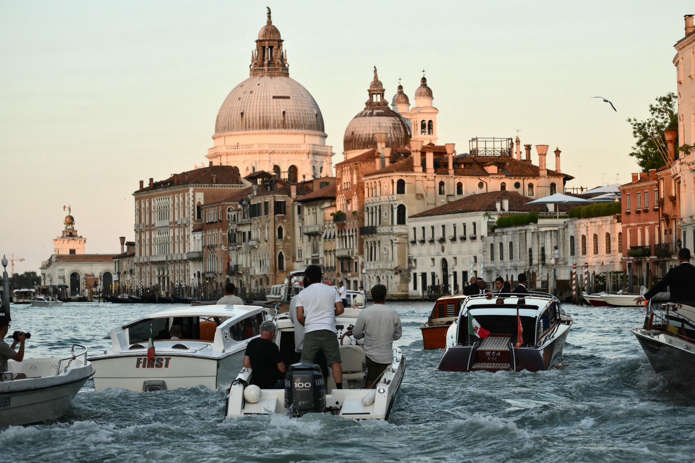 Les bateaux à moteur sillonnent le canal tandis que la lumière dorée illumine les grands dômes et les façades historiques de Venise, capturant la scène animée qui suit le bateau-taxi de Jeff Bezos et Lauren Sánchez.