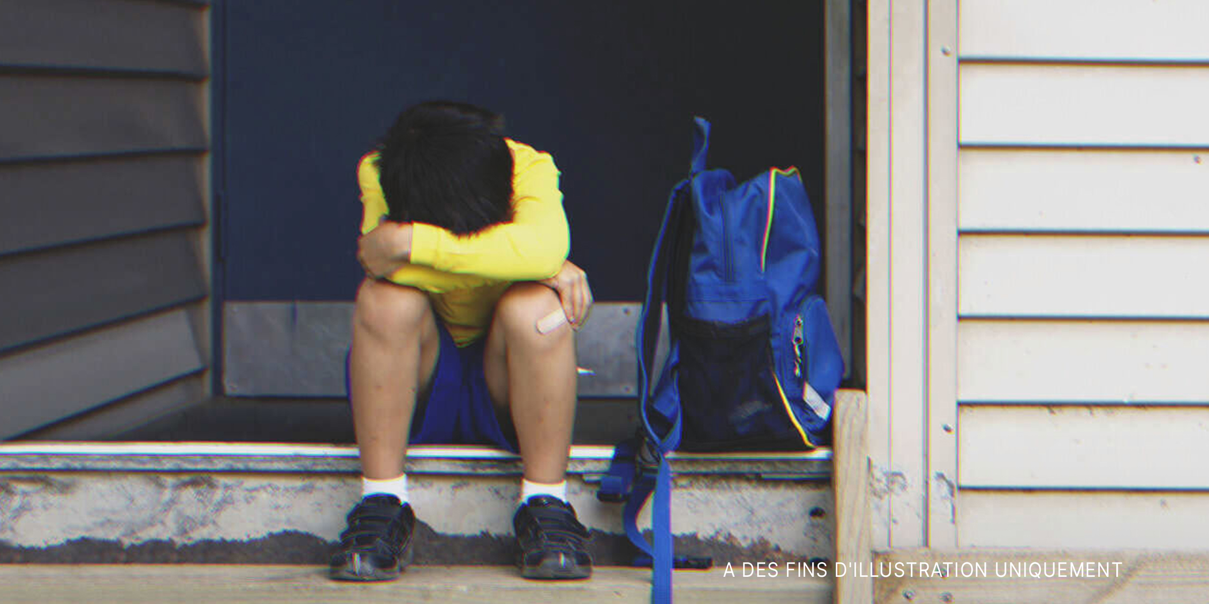 Garçon assis sur le pas de la porte | Source : Shutterstock