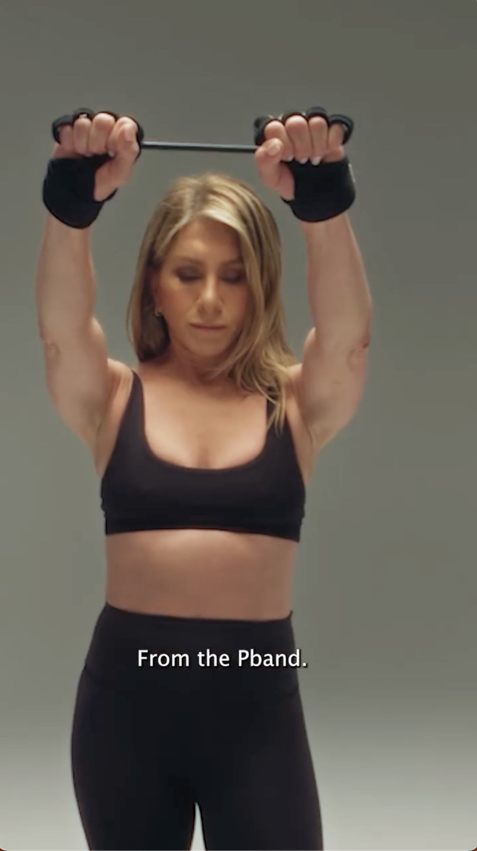 Jennifer Aniston utilise le Pband, en levant les bras avec résistance pour faire travailler ses épaules et le haut du corps | Source : Instagram/pvolve