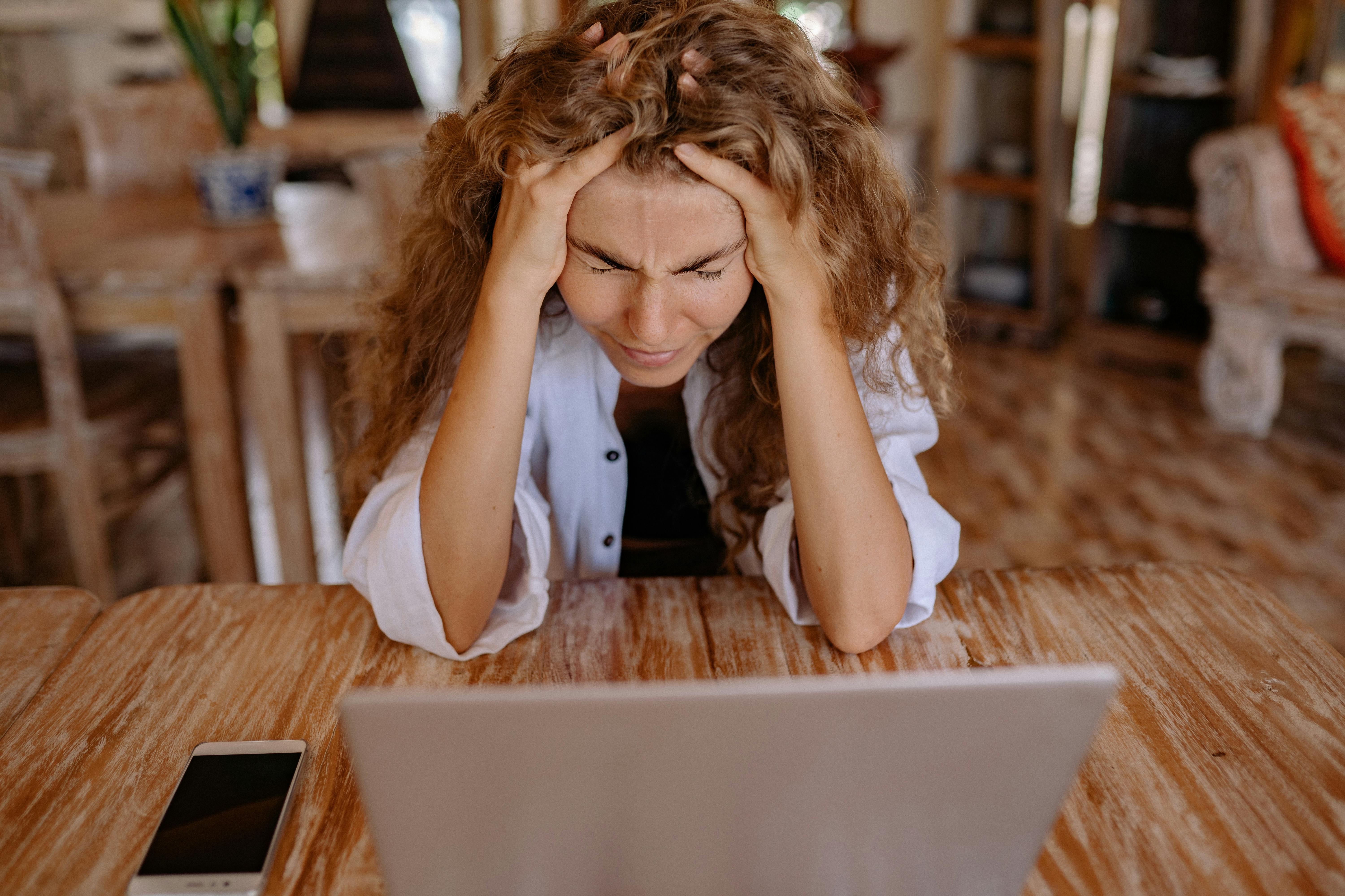 Une femme stressée avec un ordinateur portable devant elle | Source : Pexels