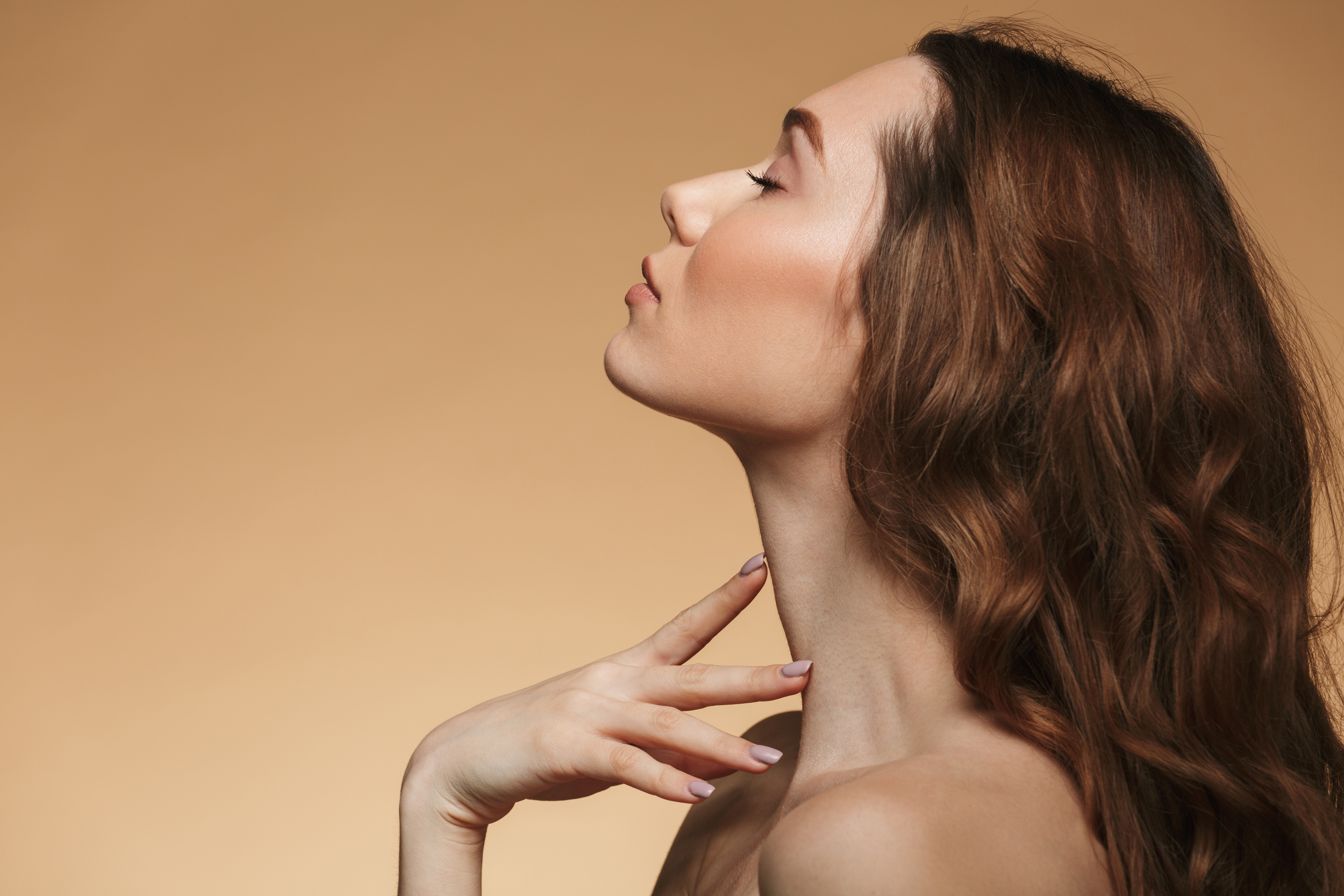 Femme aux cheveux bruns profonds fermant les yeux en penchant la tête en arrière | Source : Shutterstock