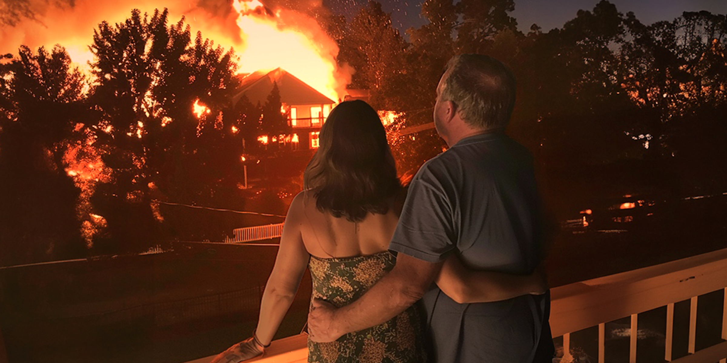 Un couple observe une maison en feu dans leur quartier | Source : Midjourney