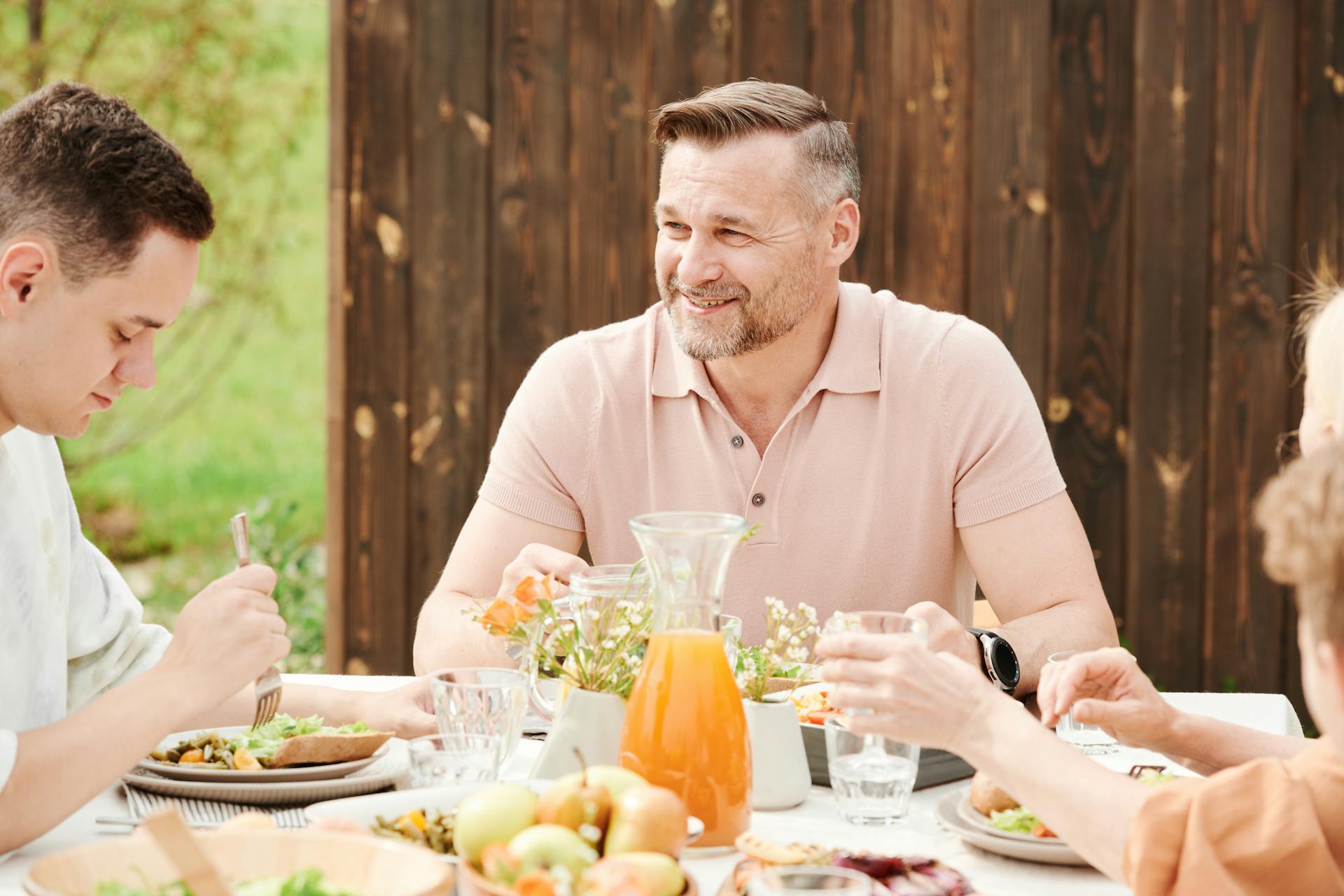 Un homme souriant à table avec sa famille | Source : Pexels