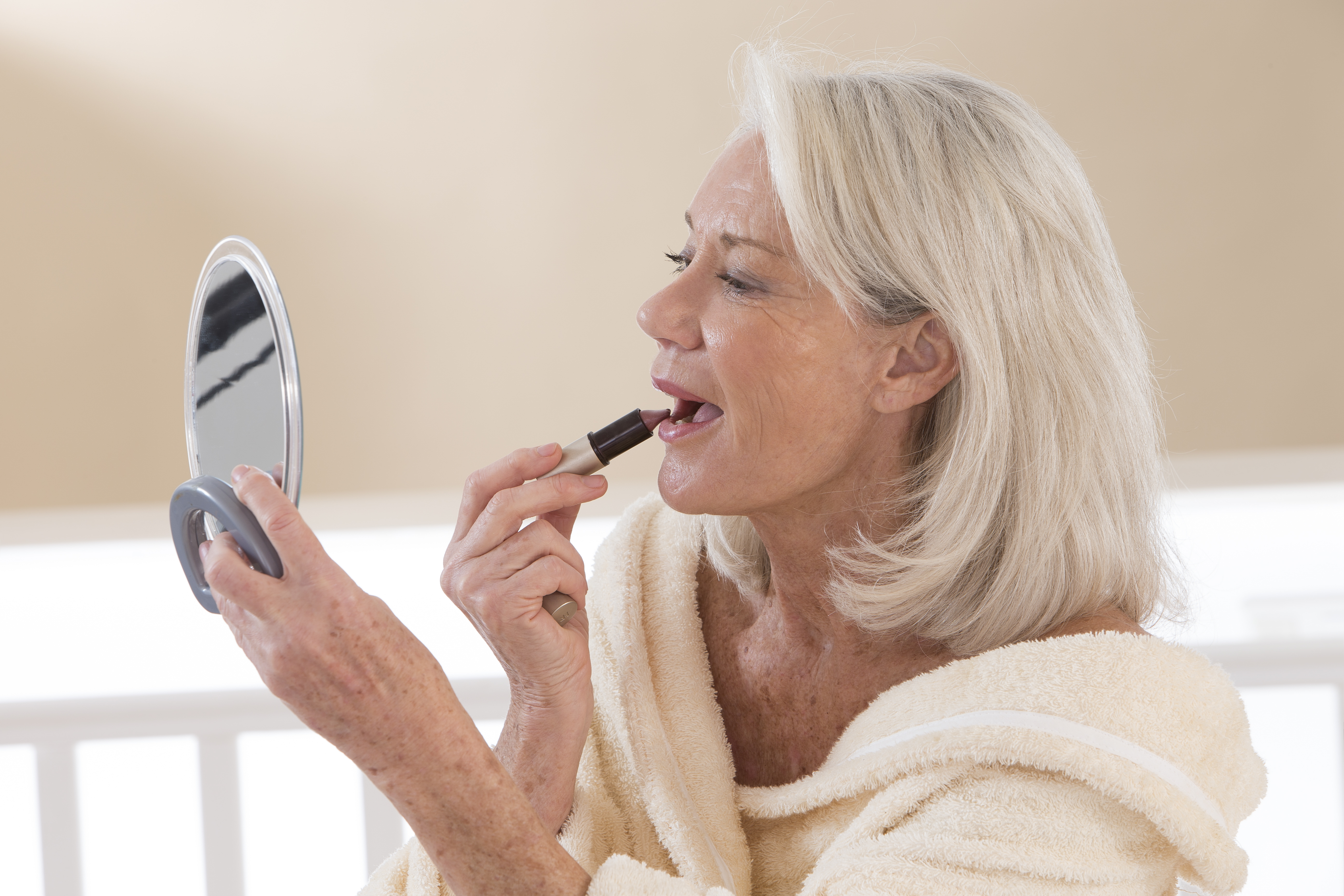 Une femme âgée qui applique du rouge à lèvres | Source : Shutterstock