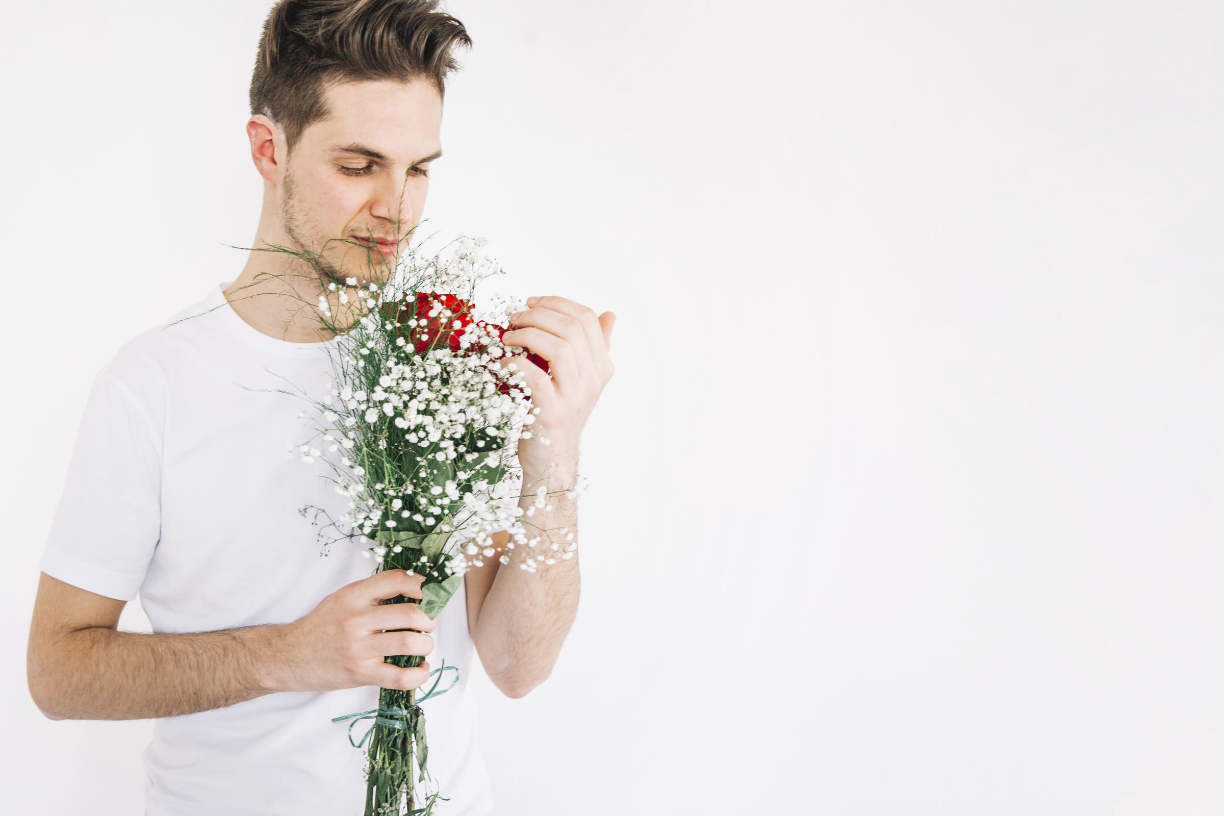 Un jeune homme avec des fleurs | Source : Freepik