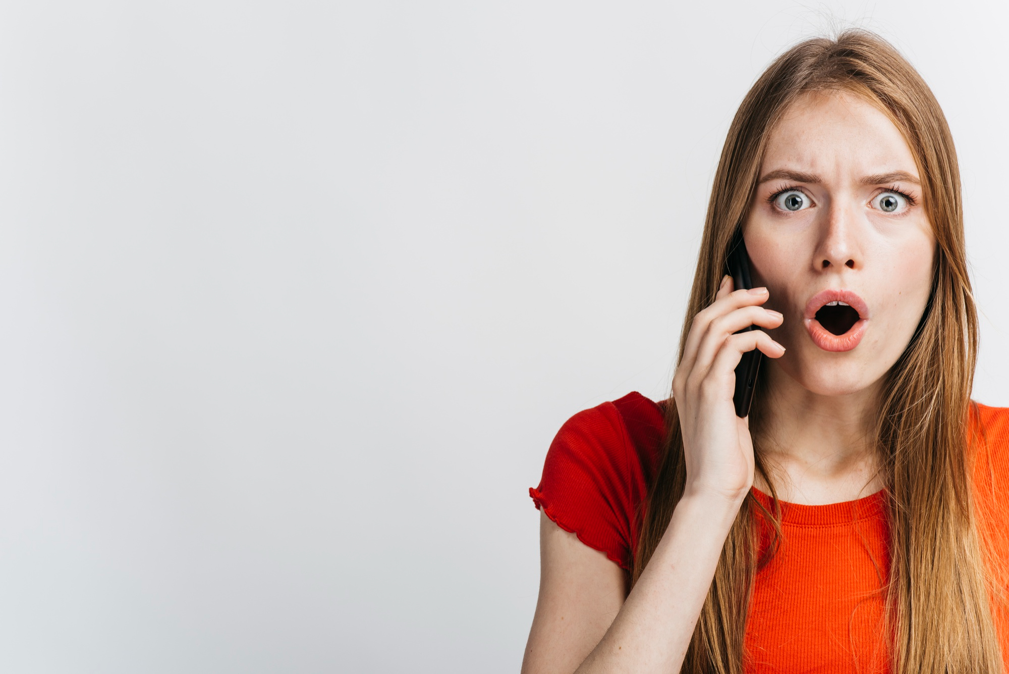 Une femme réagissant en état de choc lors d'un appel téléphonique | Source : Freepik