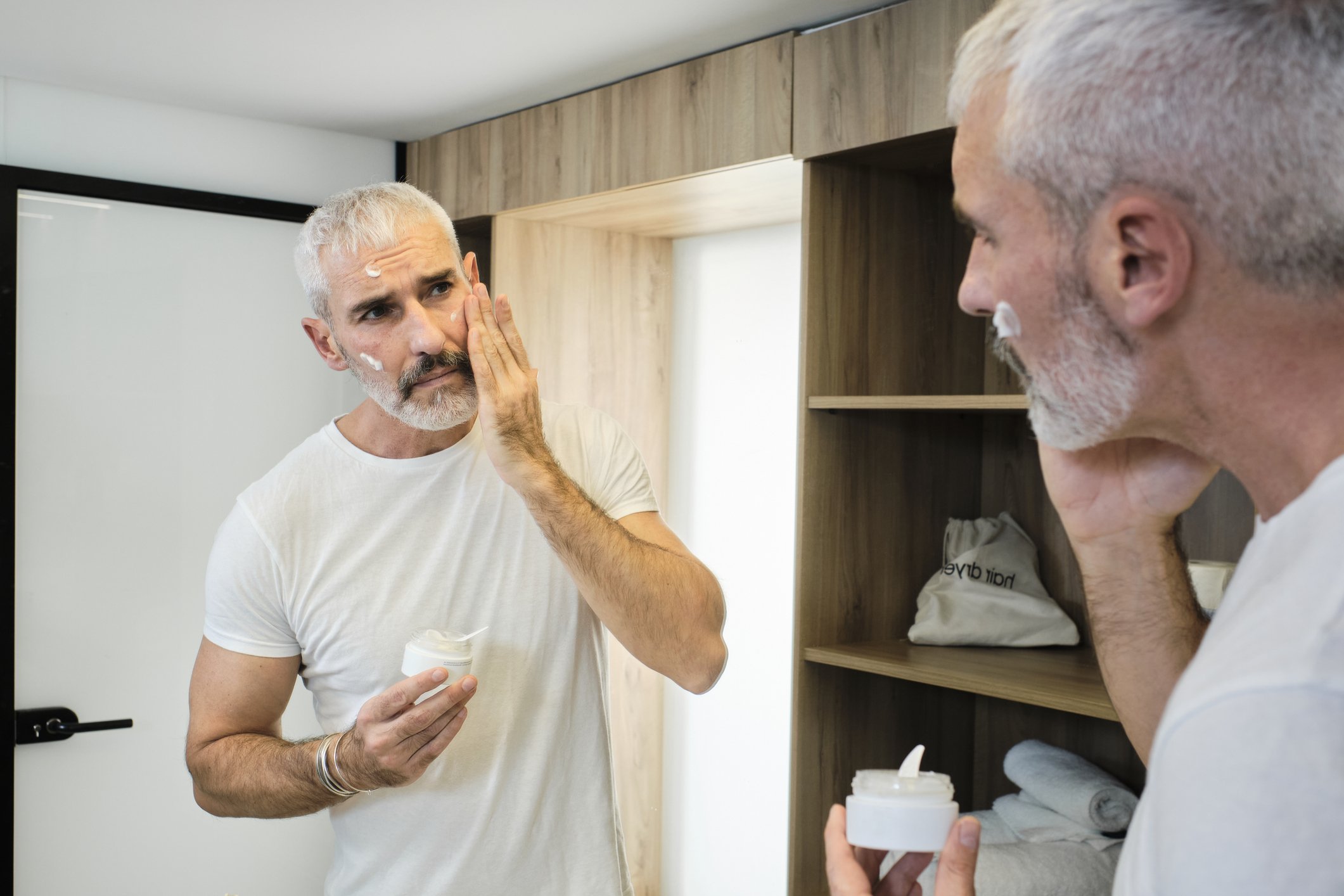 Un homme d'âge mûr applique une crème pour le visage. | Photo : Getty Images