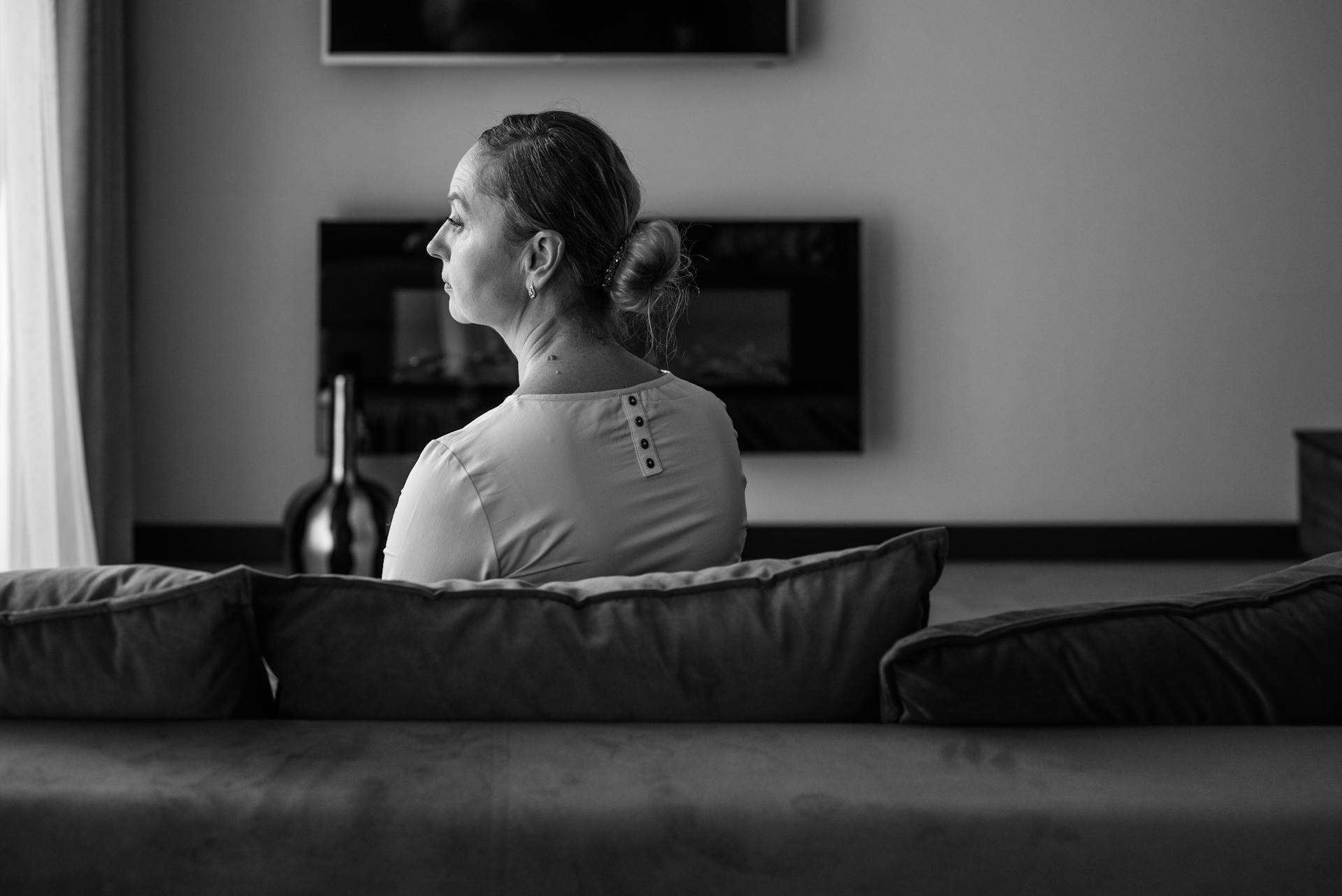 Photo en niveaux de gris d'une femme assise seule sur le canapé | Source : Pexels