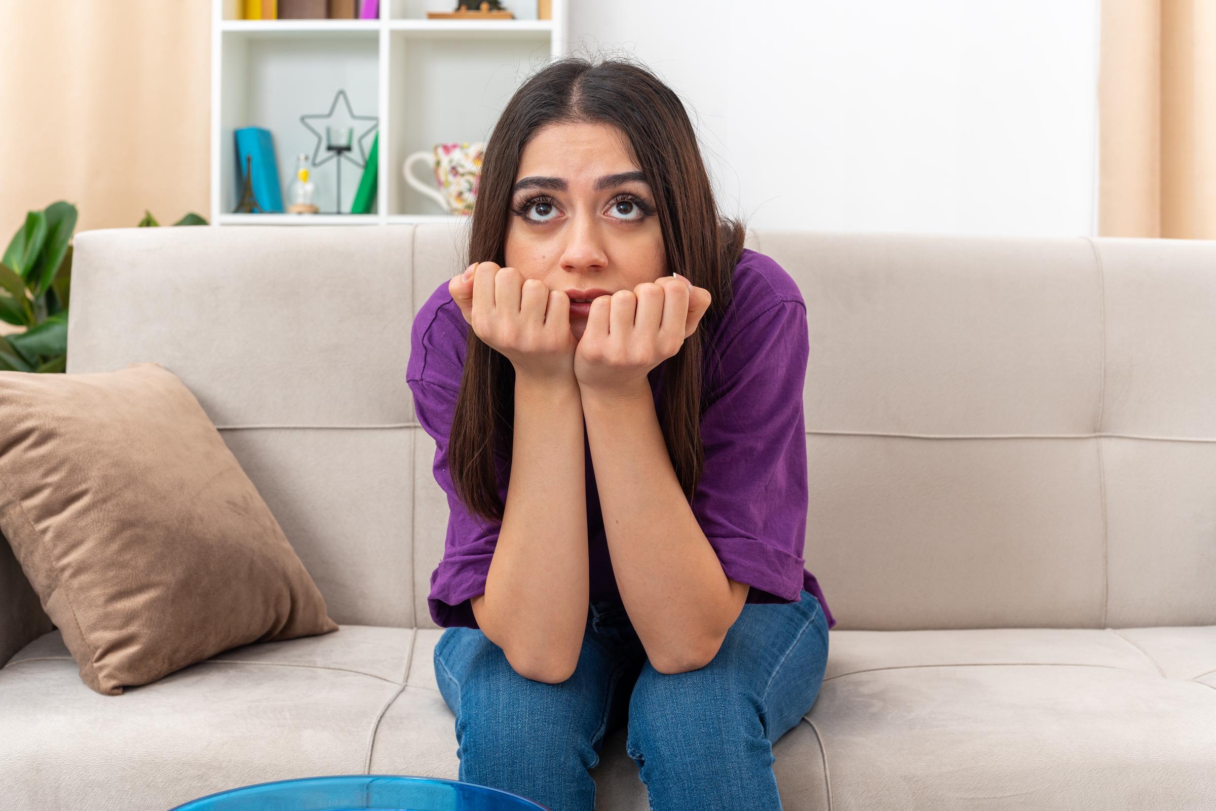 Une jeune femme bouleversée assise sur le canapé | Source : Freepik