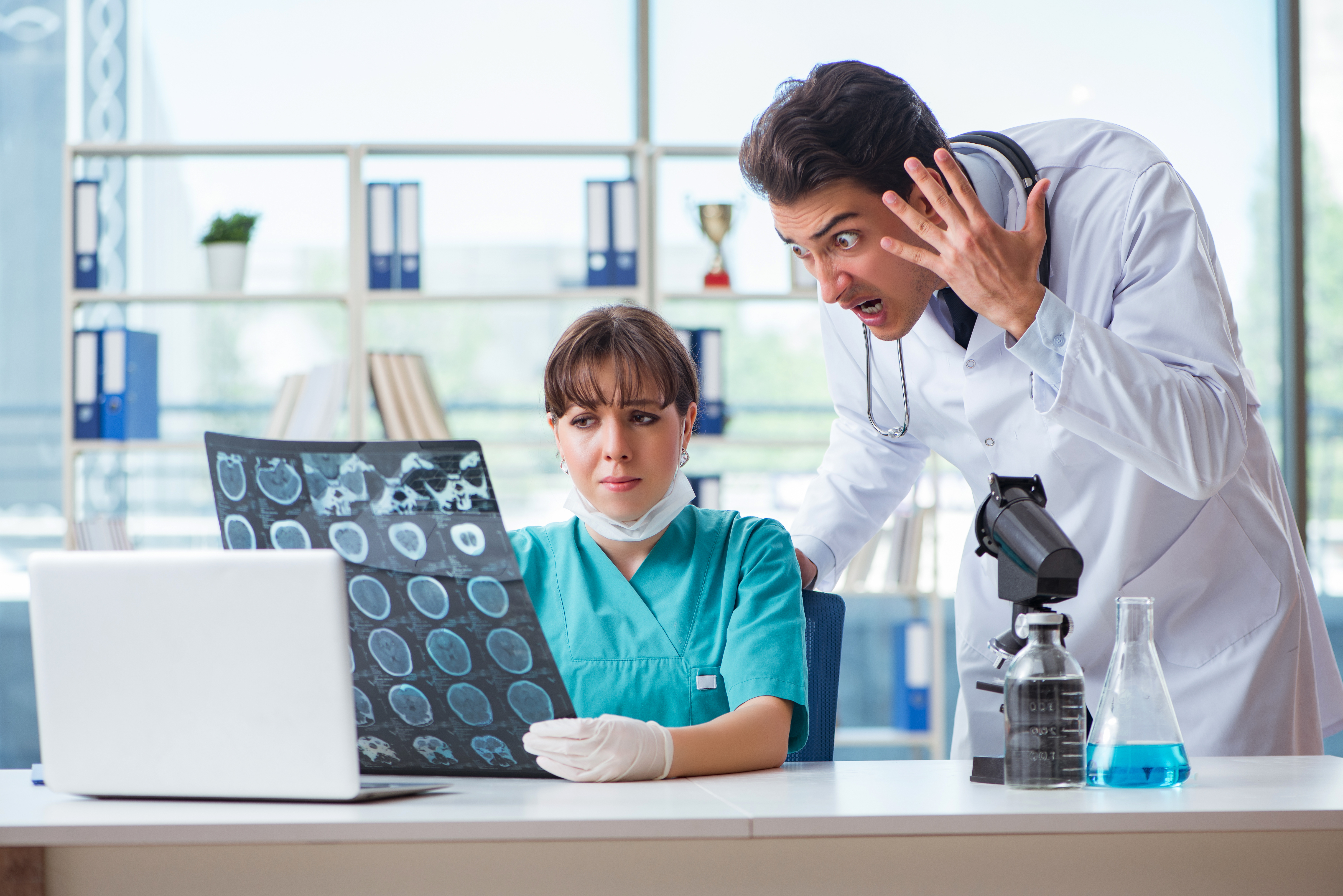 Un médecin criant tout en regardant une image IRM tenue par un autre professionnel de la santé | Source : Shutterstock