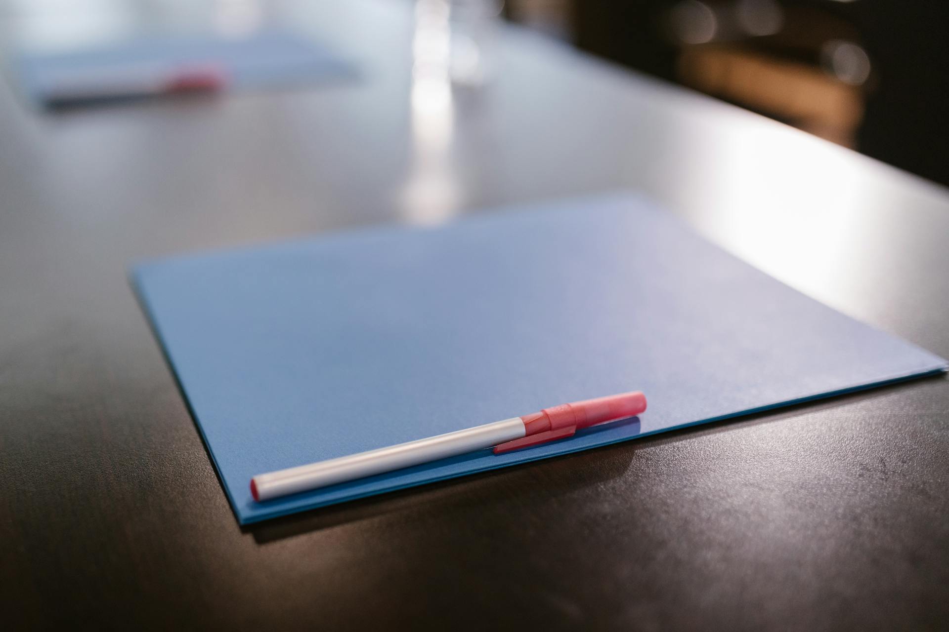 A pen above a blue folder on a table | Source: Pexels