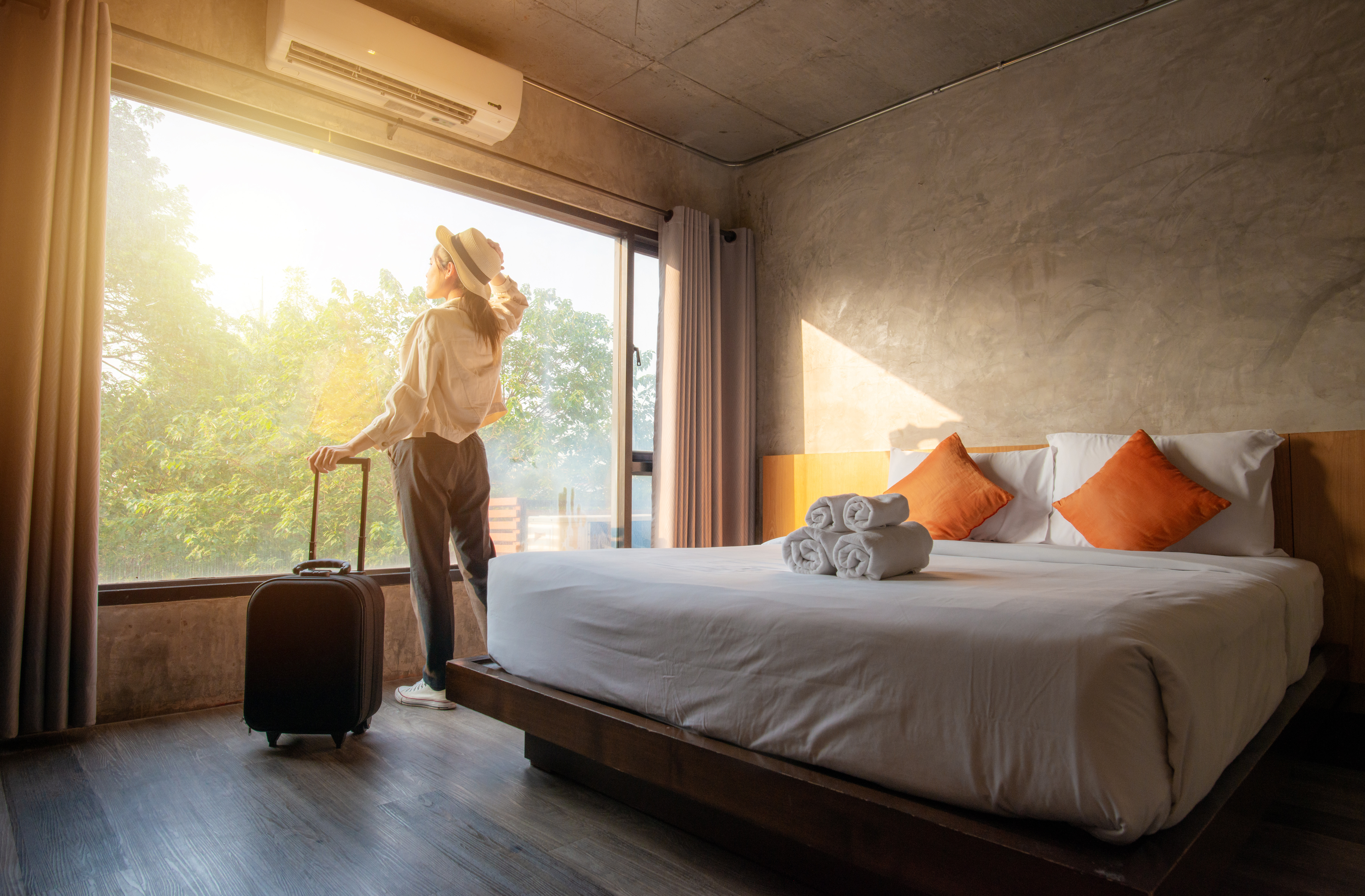 Une touriste profite de la vue à l'extérieur de sa chambre d'hôtel après l'enregistrement | Source : Shutterstock