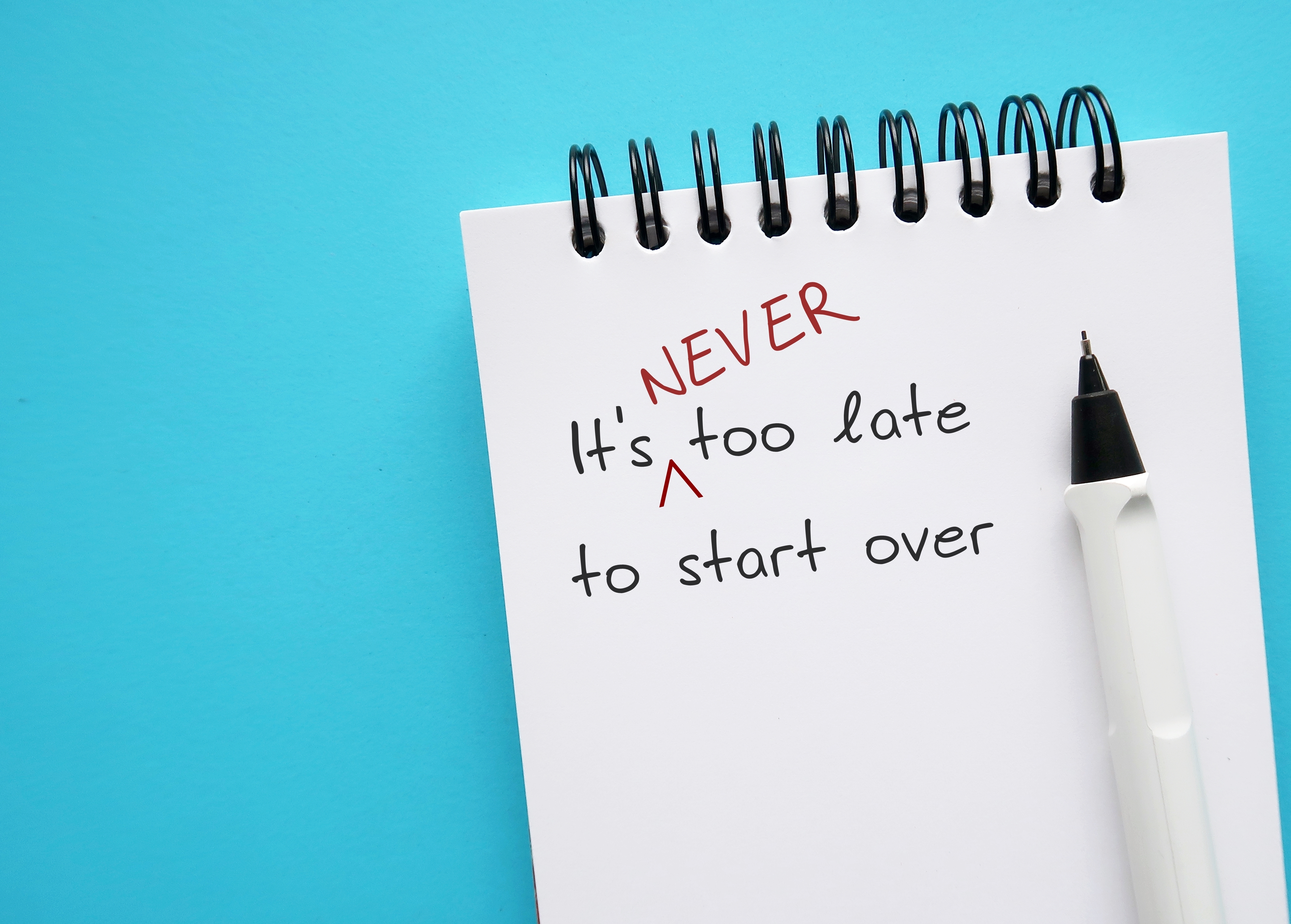 Un cahier avec les mots "Il n'est jamais trop tard pour recommencer" griffonnés sur une page | Source : Shutterstock