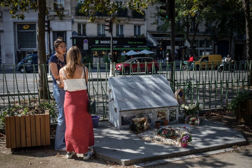 Des femmes se tiennent près de la plaque commémorative des victimes des attaques terroristes de novembre 2015 à Paris, le 8 septembre 2021, près du théâtre et du café Bataclan, Paris, France. | Photo : Getty Images