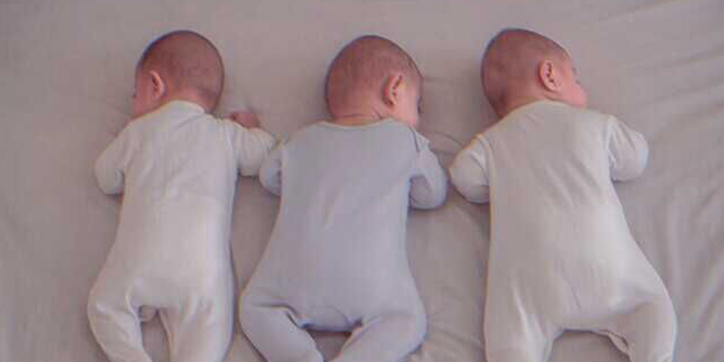 Trois bébés allongés dans un lit | Source : Unsplash