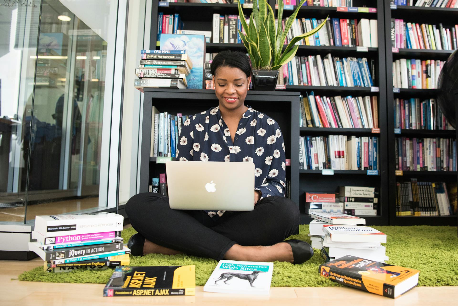 Une femme navigue sur son ordinateur portable alors qu'elle est assise dans une bibliothèque | Source : Pexels