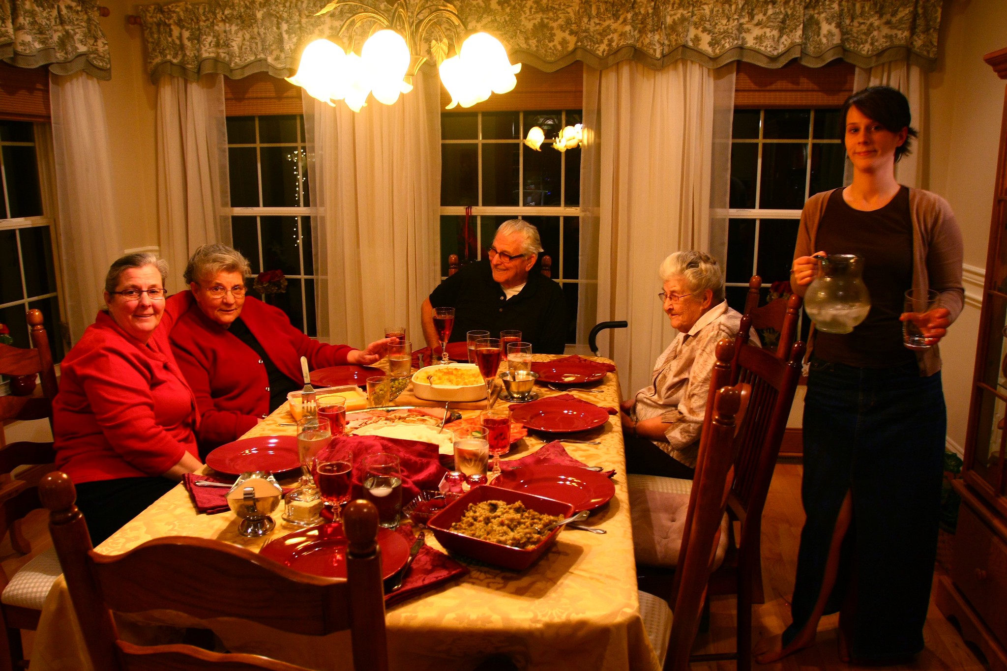 Une femme serveur se tenant près d'une famille réunie pour le repas de Noël | Source : Flickr