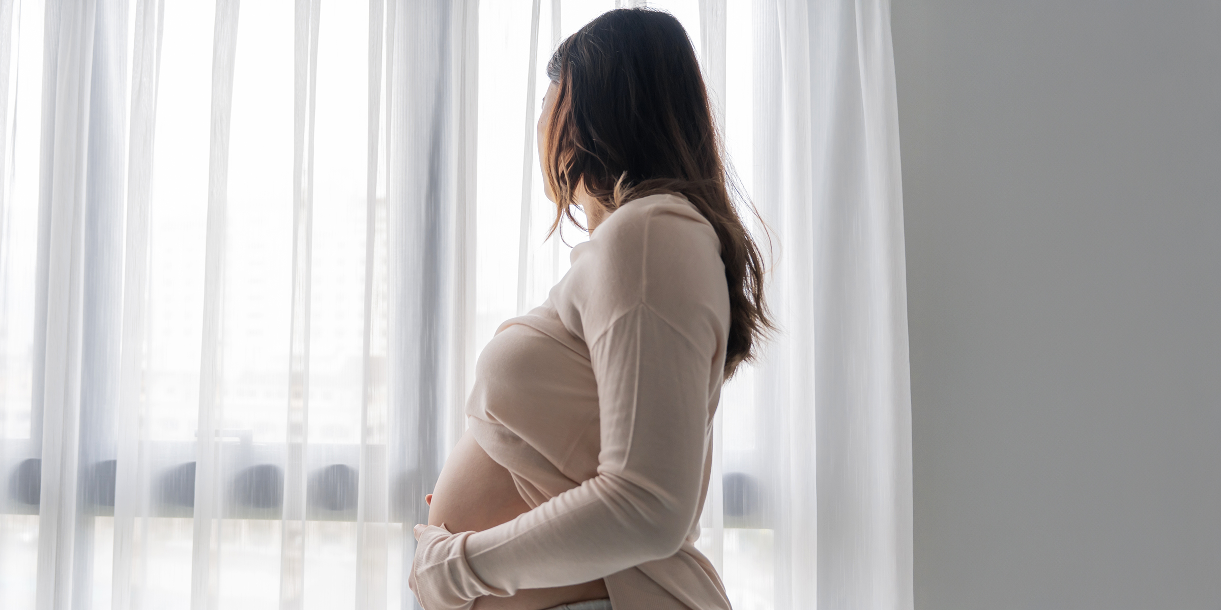 Une femme enceinte qui regarde à l'extérieur d'une fenêtre | Source : Shutterstock