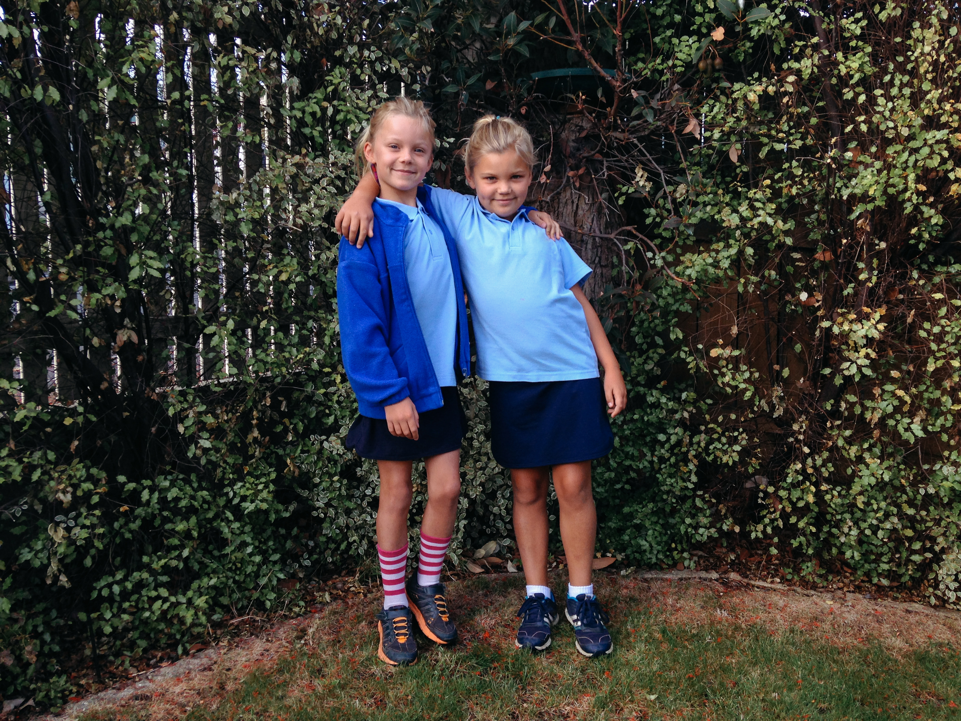 Deux sœurs portant des uniformes scolaires se tiennent ensemble, les bras enlacés | Source : Getty Images