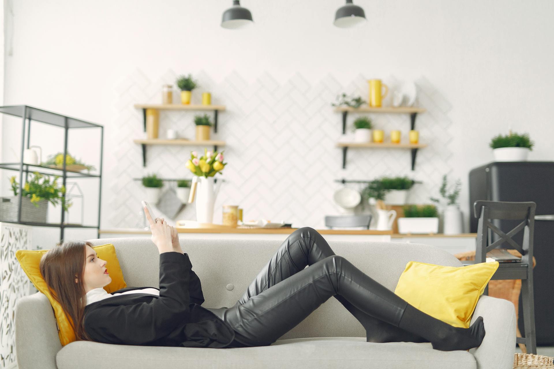Une femme allongée sur le canapé et utilisant son téléphone | Source : Pexels
