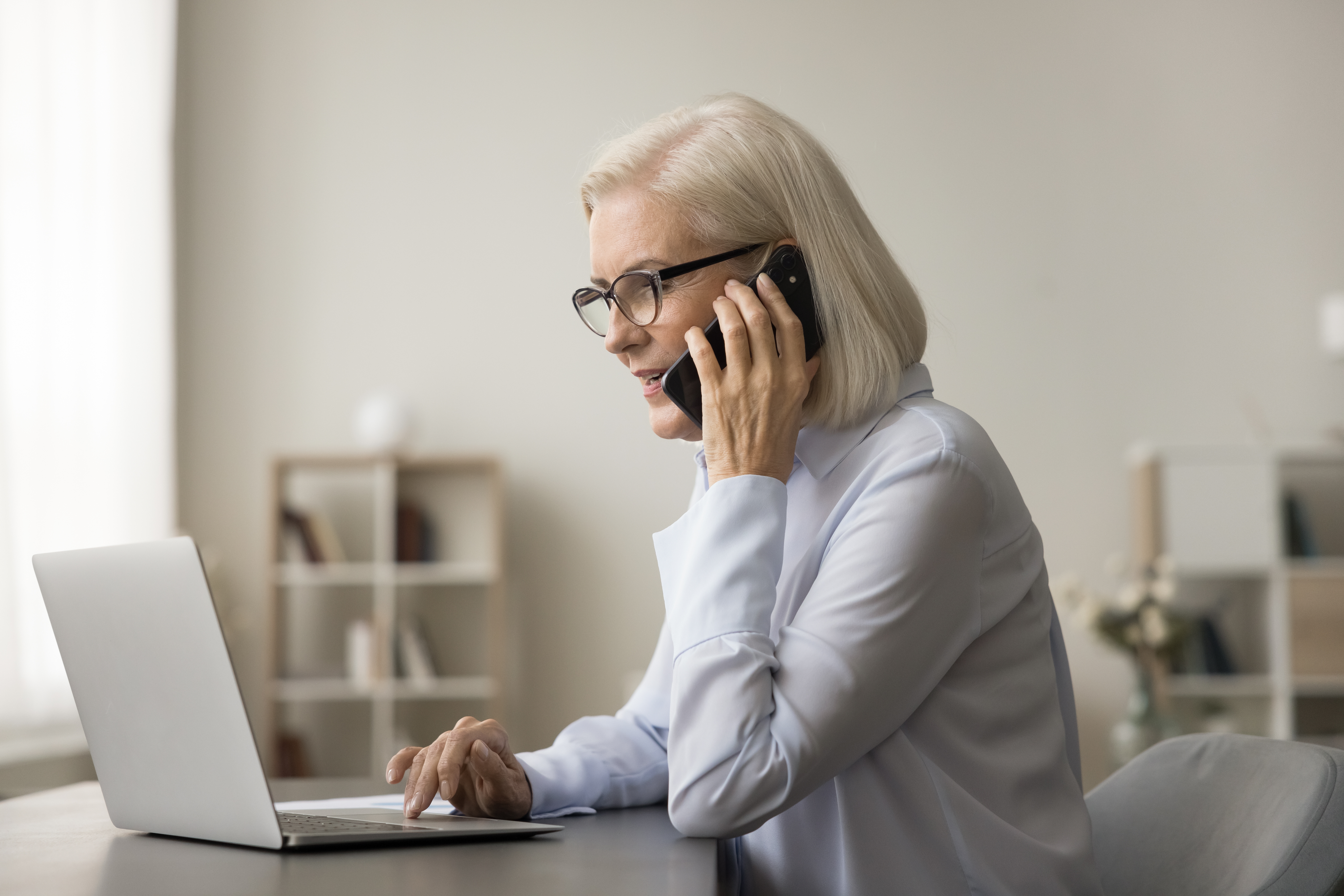 Femme parlant au téléphone devant un ordinateur portable | Source : Shutterstock