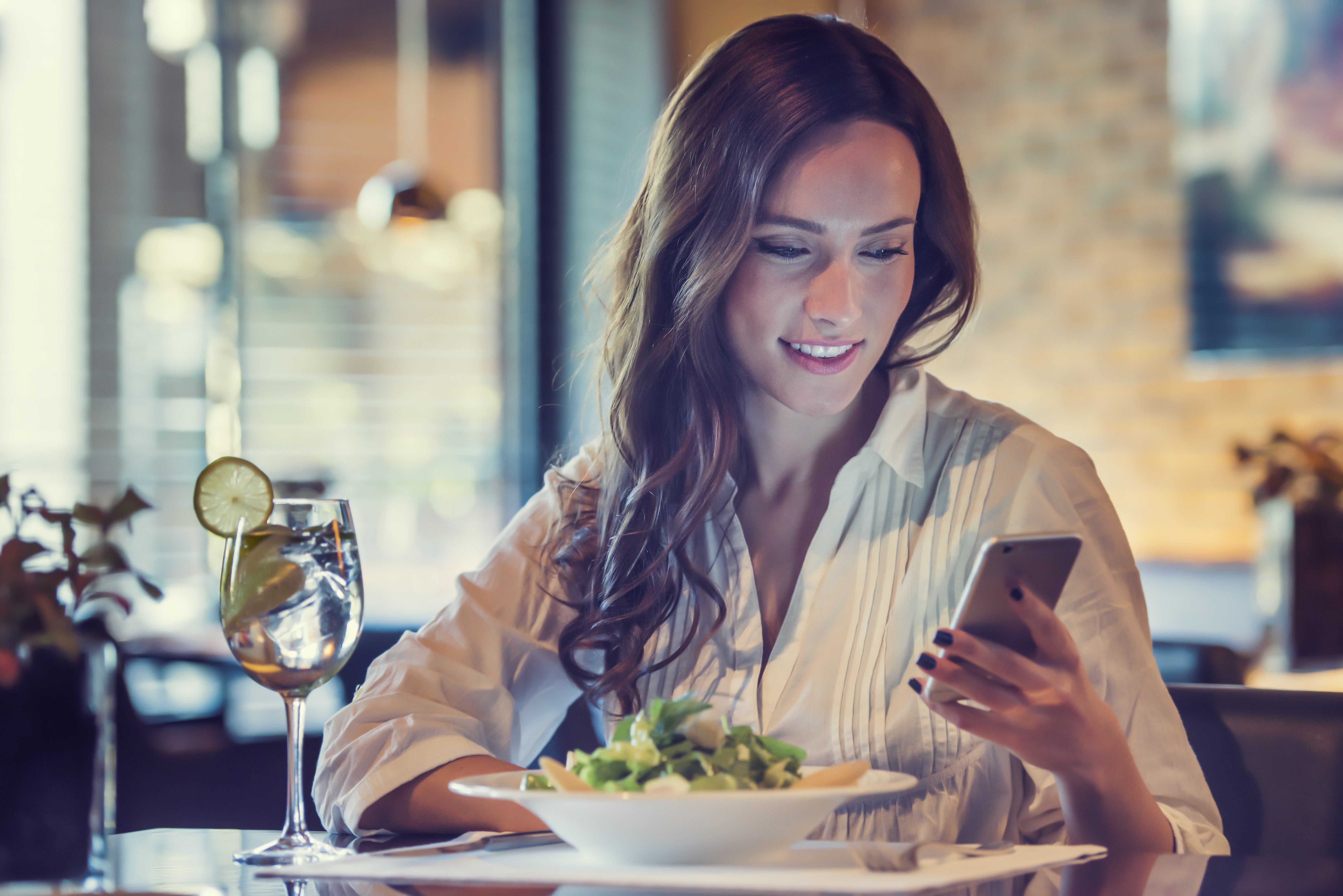 Une jeune femme utilisant son téléphone dans un restaurant | Source : Shutterstock