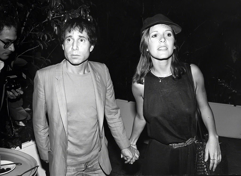 Paul Simon et Carrie Fisher se tenant la main lors d'une sortie à New York le 1er janvier 1980. | Photo : Getty Images.
