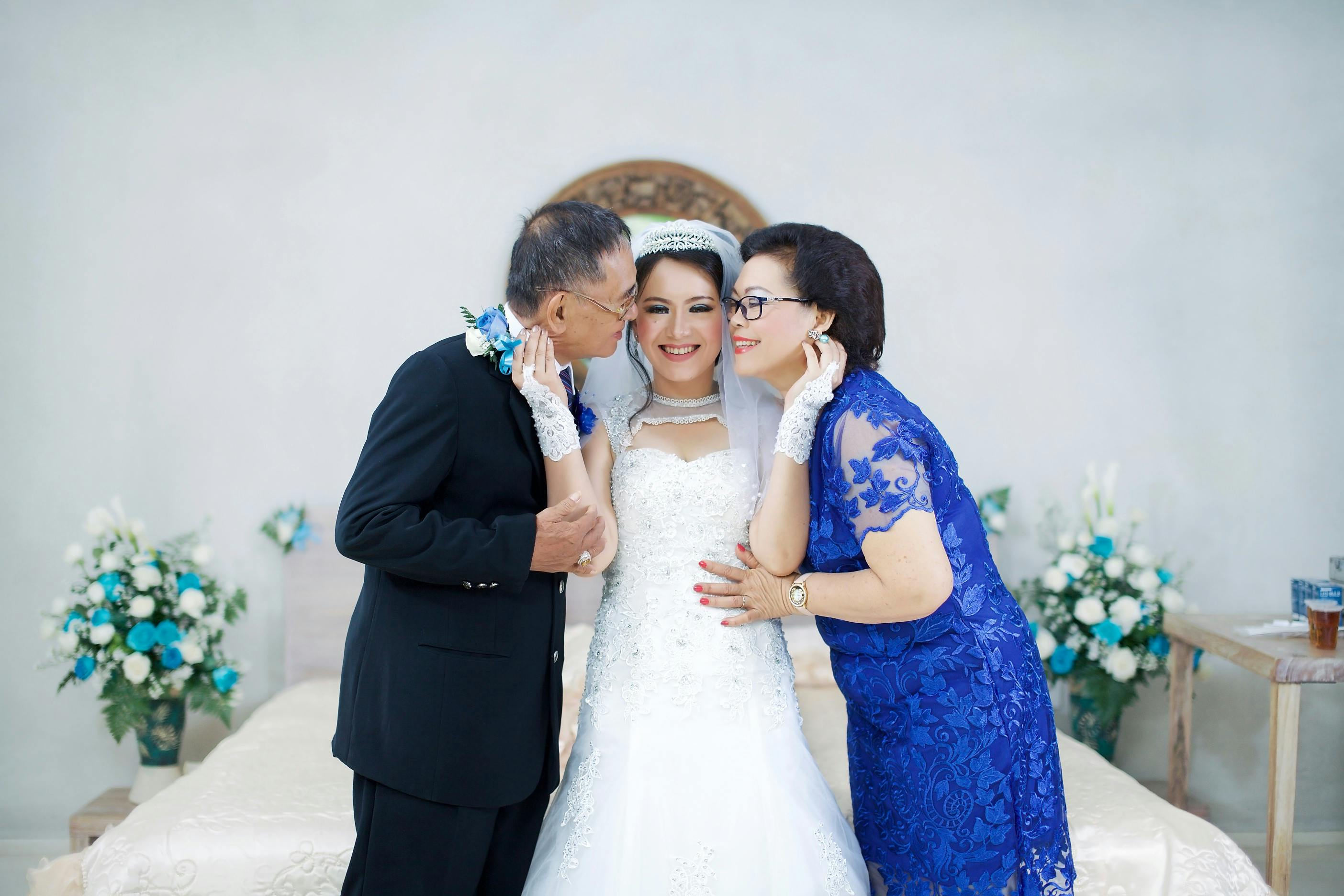 Une mariée heureuse posant avec ses parents le jour de son mariage | Source : Pexels