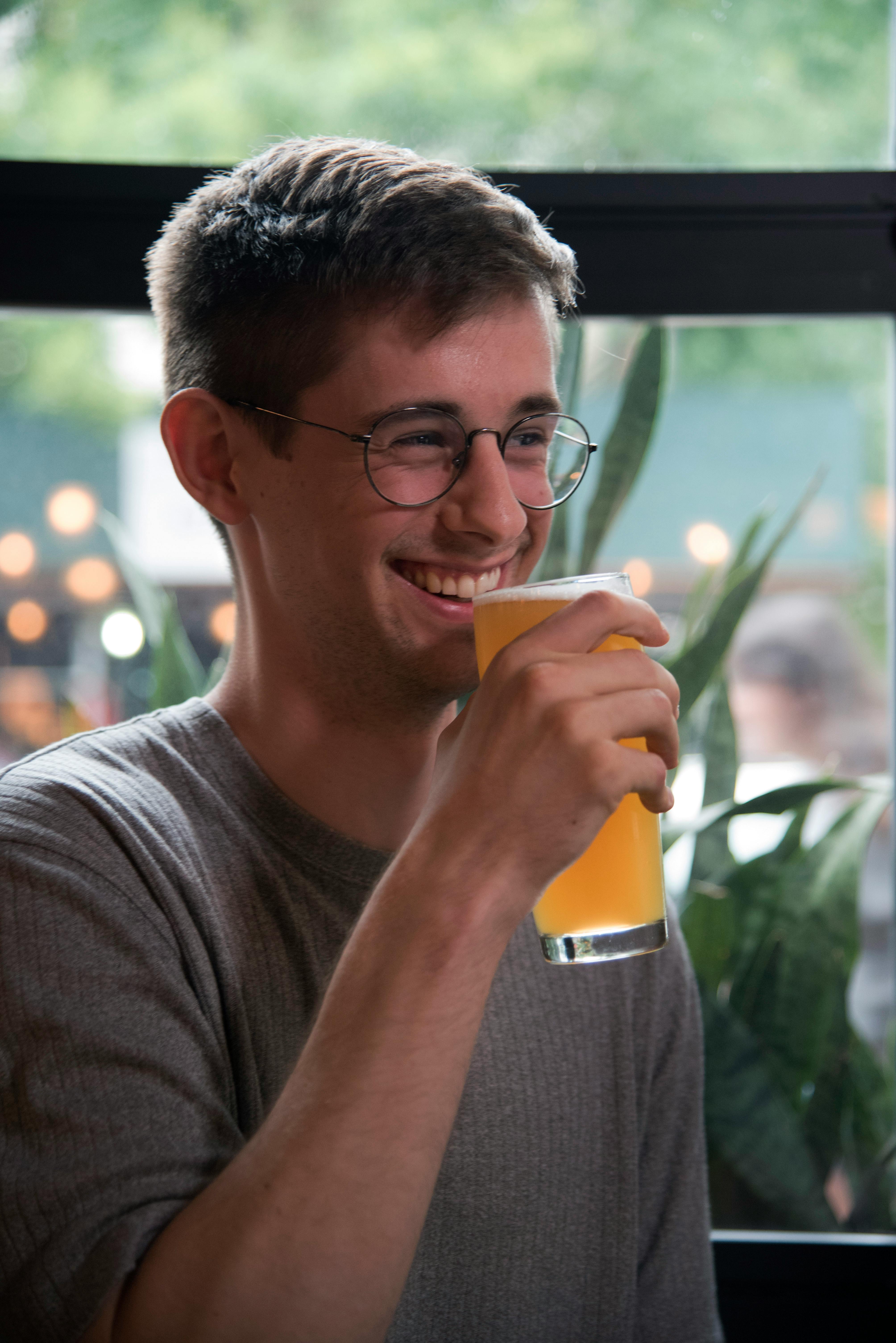 Un homme qui boit une boisson en riant | Source : Pexels