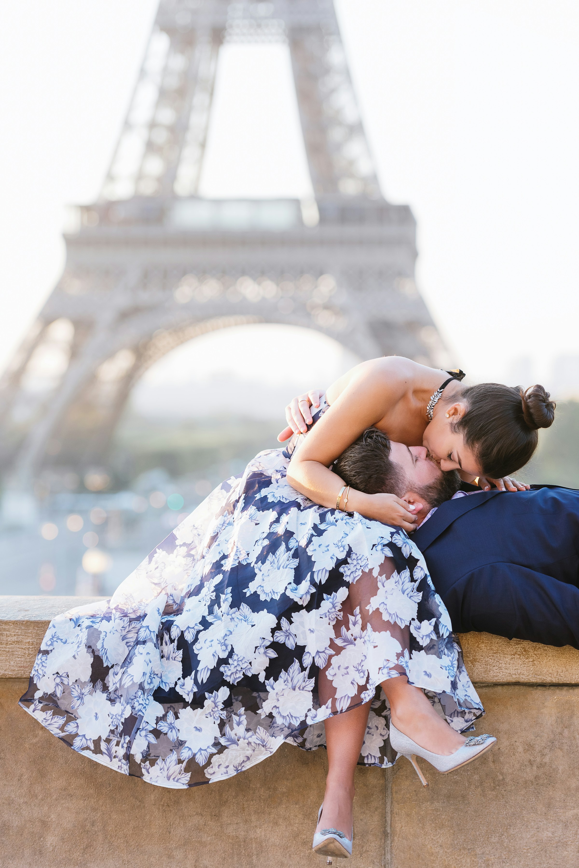 Un couple s'embrasse sur un rebord devant la Tour Eiffel à Paris | Source : Unsplash