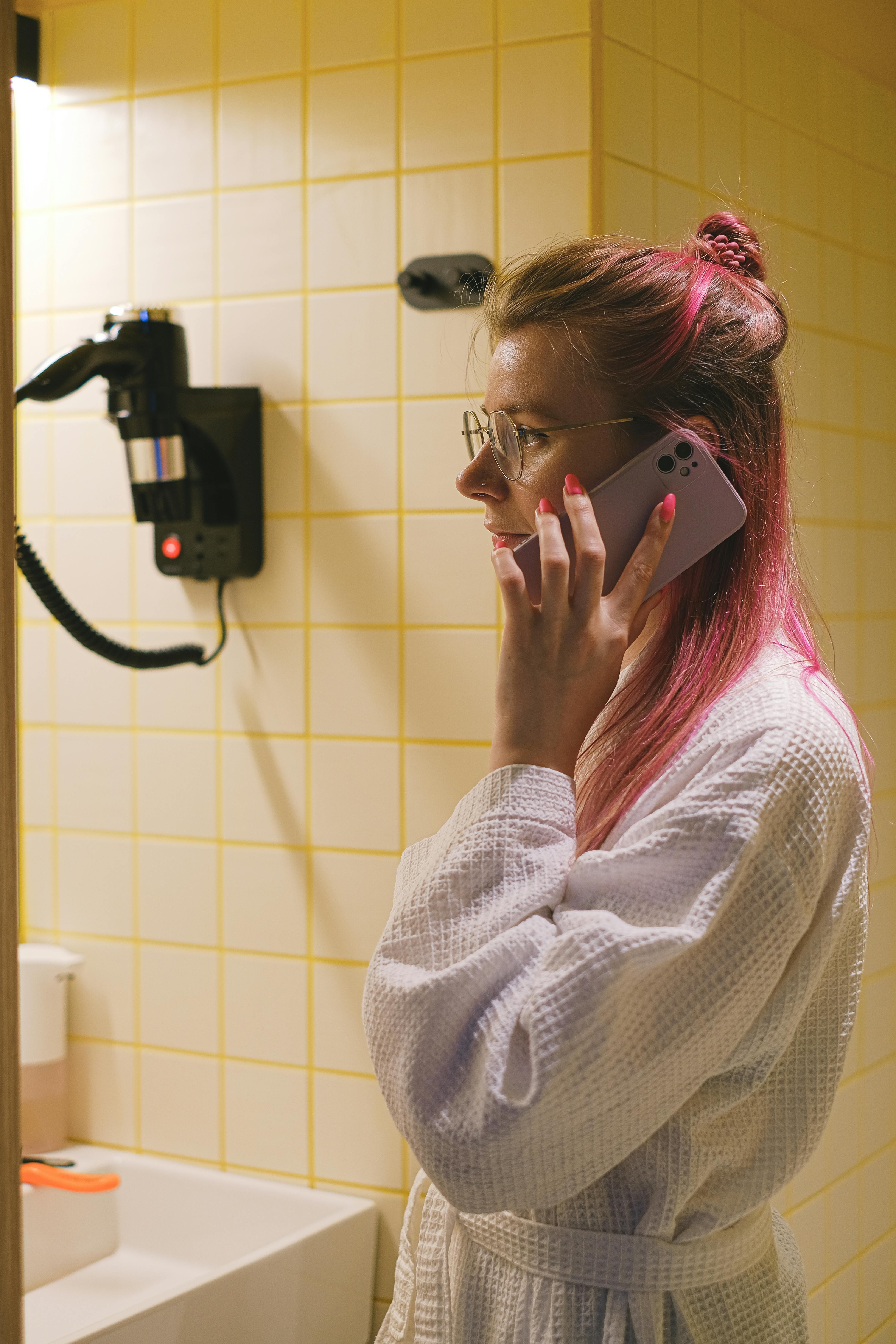 Une femme qui parle au téléphone dans une salle de bain | Source : Pexels
