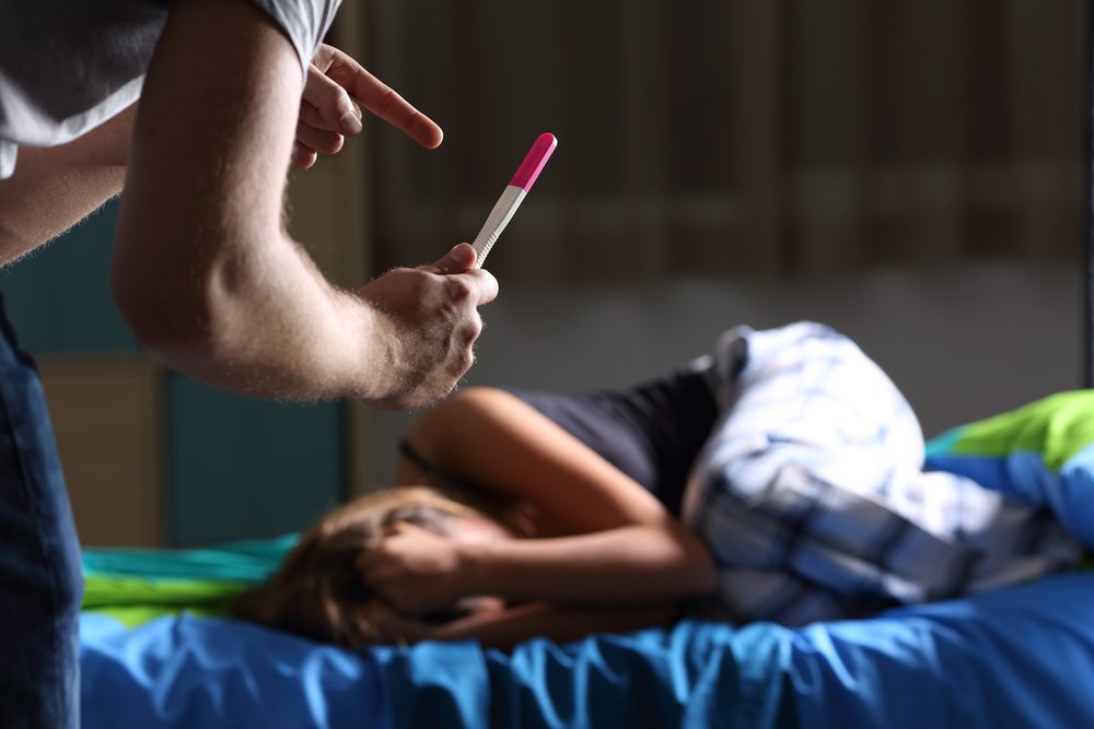 Le père demande des explications pour montrer un test de grossesse à une adolescente enceinte triste | Photo : Shutterstock