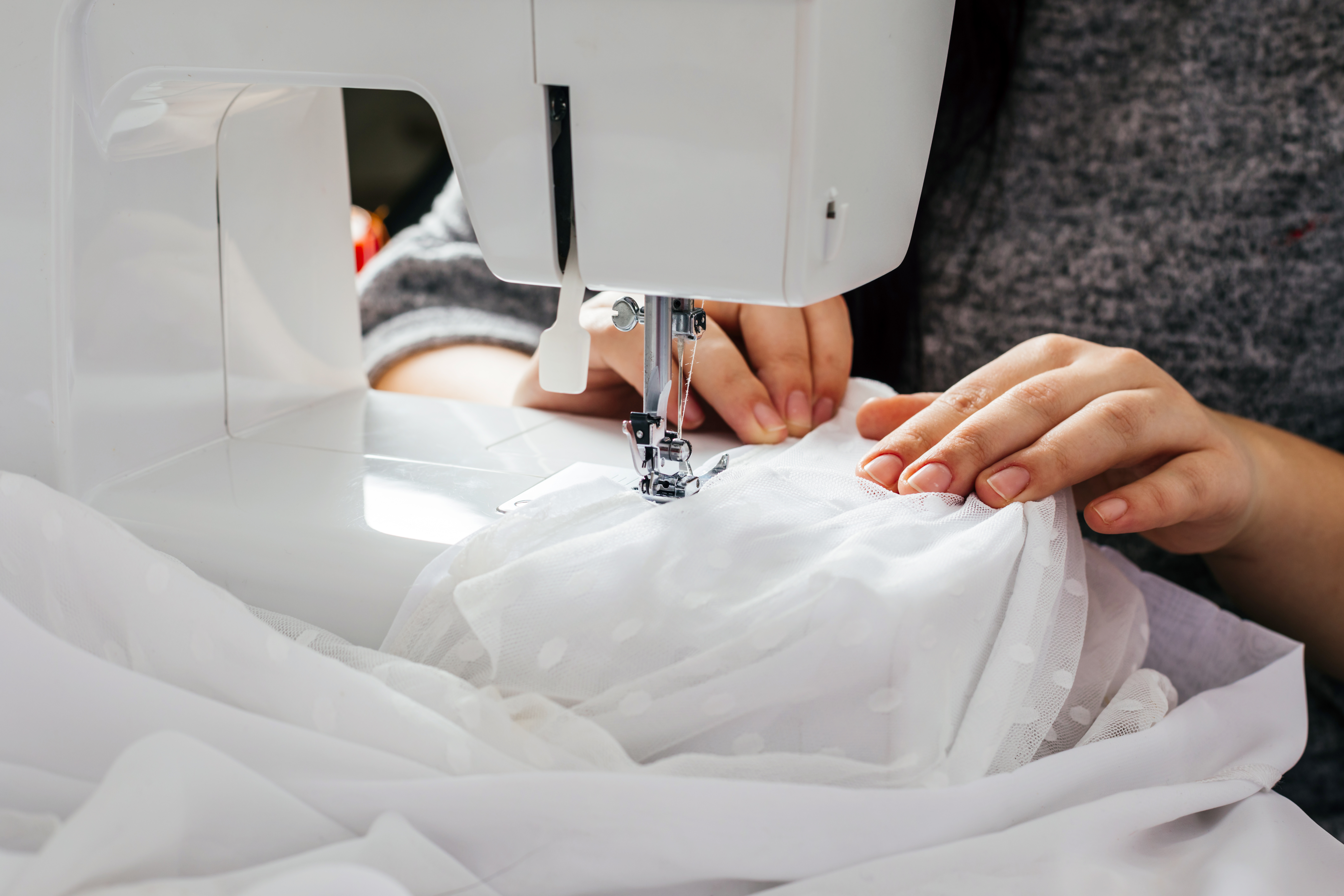 Une couturière en train de coudre une robe de mariée. | Source : Shutterstock