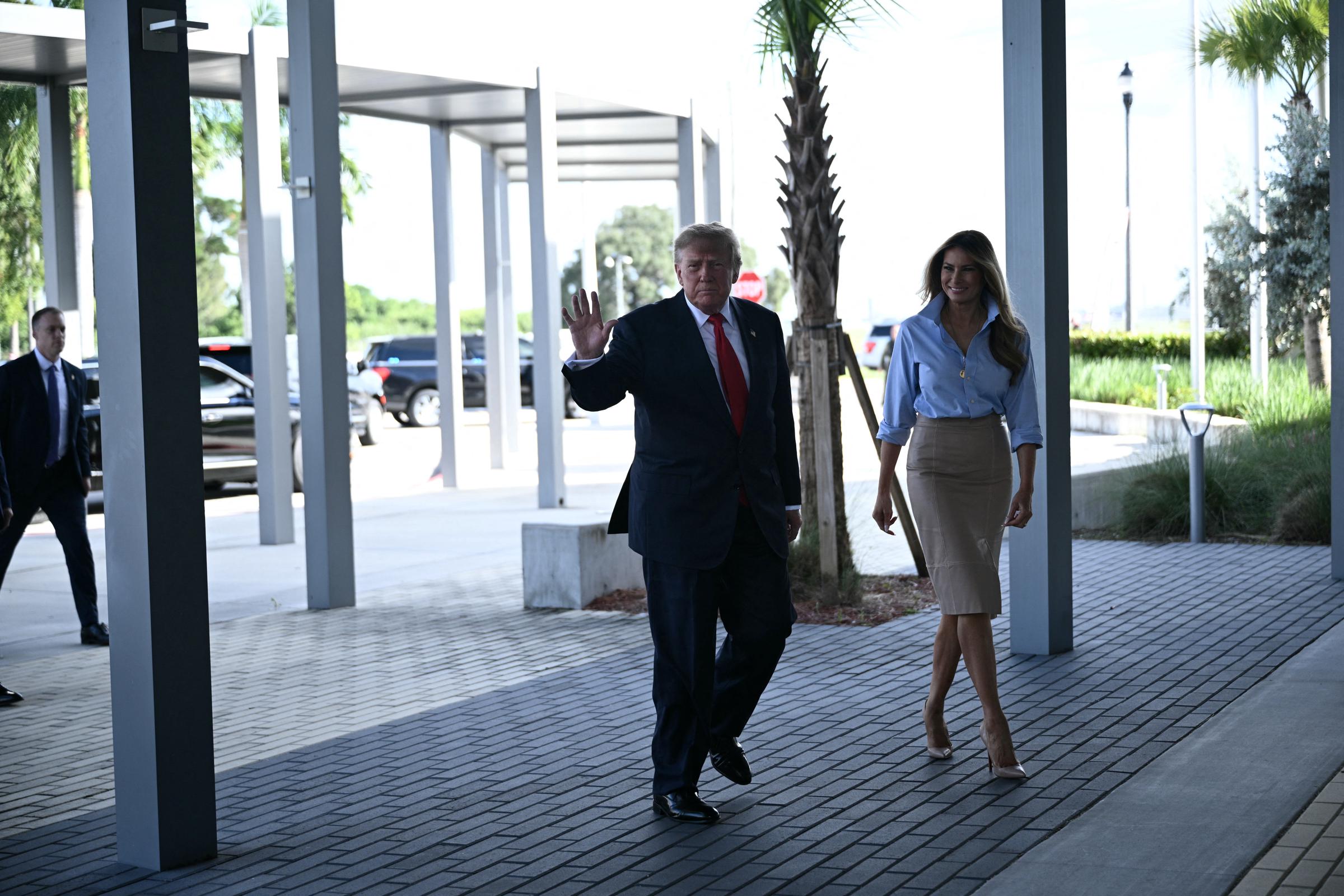 Aux côtés de Donald Trump, qui salue les passants le long de la passerelle extérieure baignée de soleil, Melania met en valeur les lignes épurées de sa tenue sur mesure, avançant dans d'immenses escarpins Christian Louboutin couleur chair à bout pointu qui rehaussent avec élégance la jupe arrivant sous le genou.