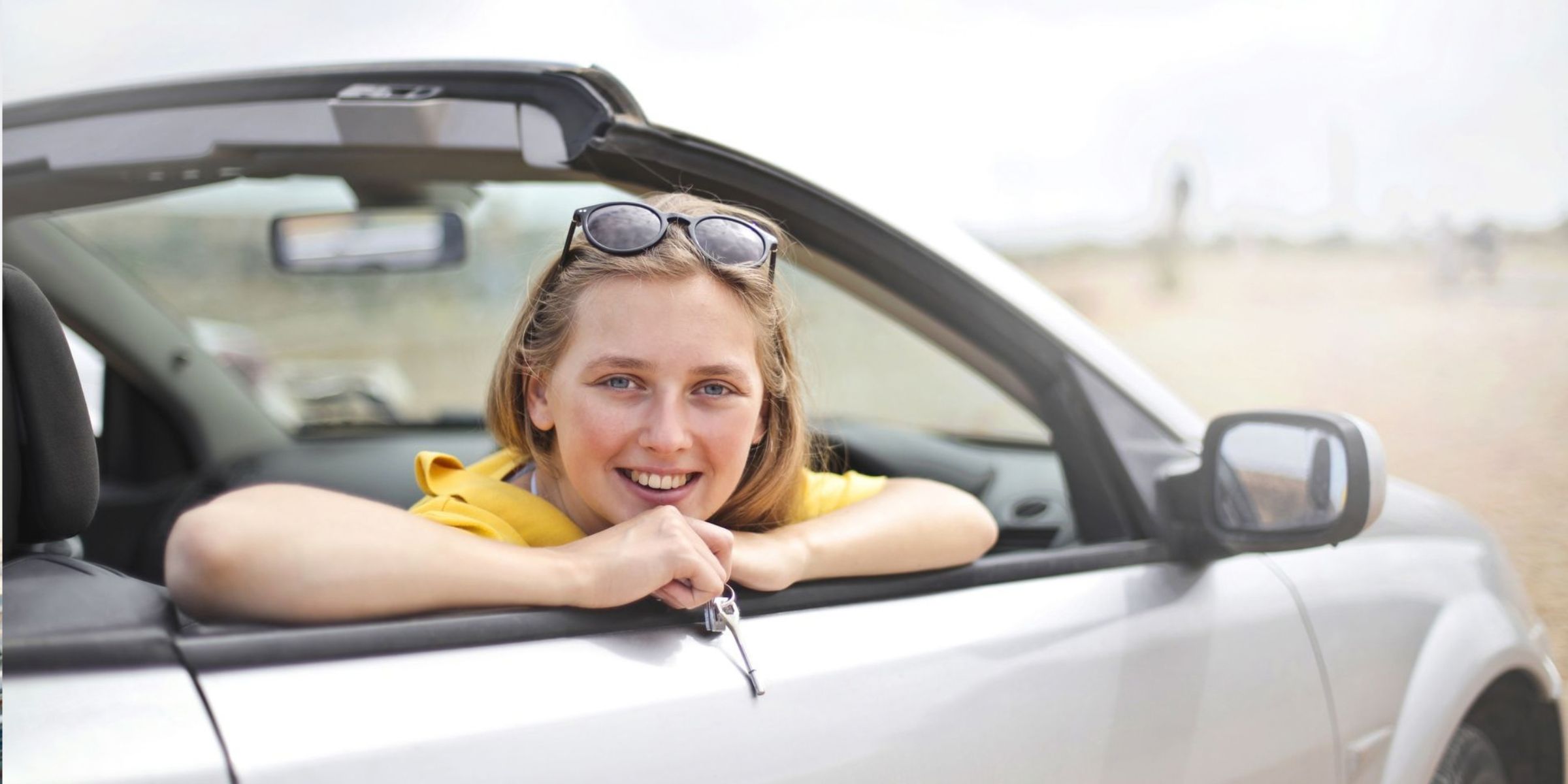 Une jeune femme sourit joyeusement, la tête penchée par la fenêtre d'une décapotable | Source : Pexels
