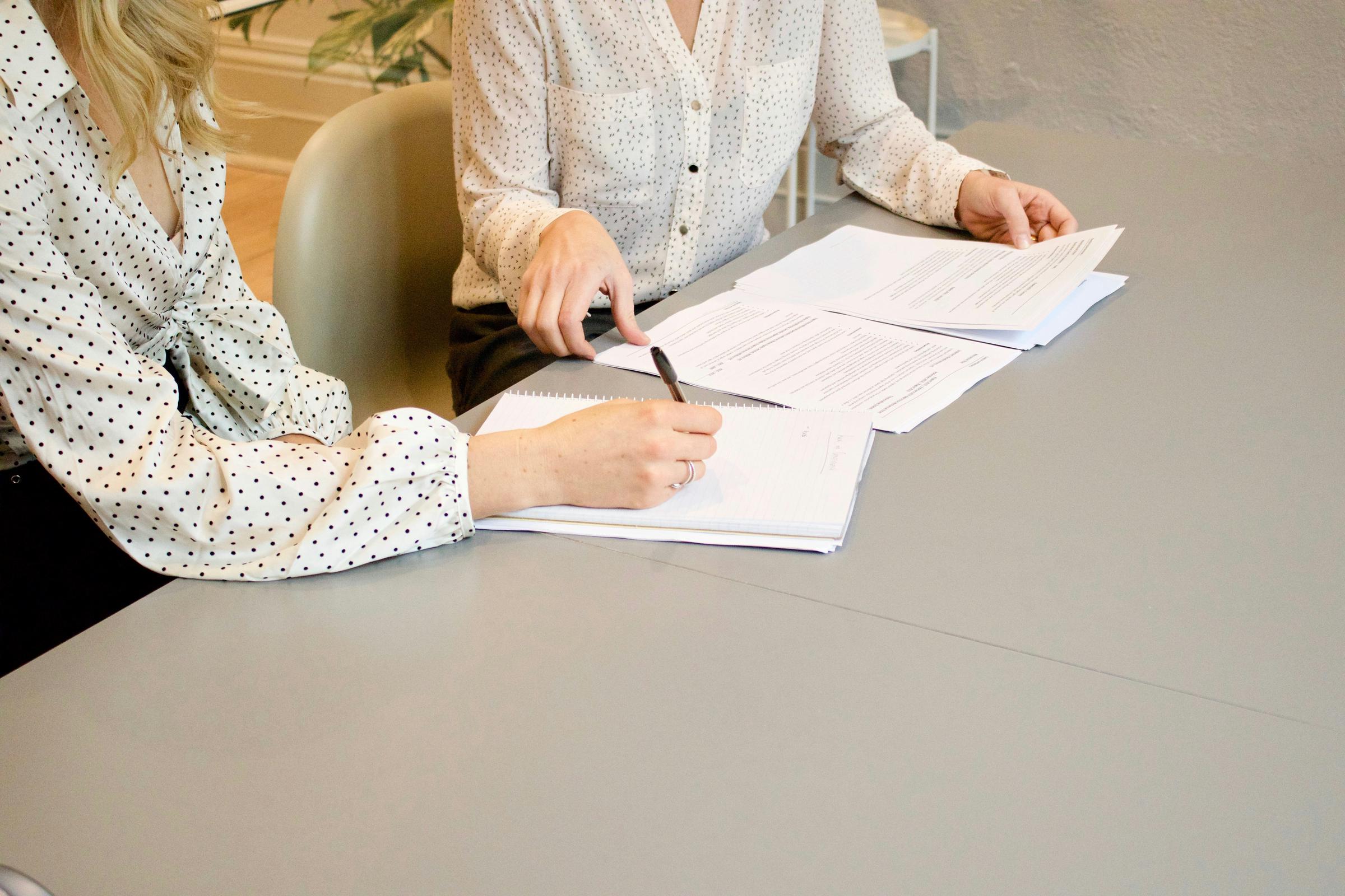 Deux femmes assises à une table avec de la paperasse | Source : Unsplash