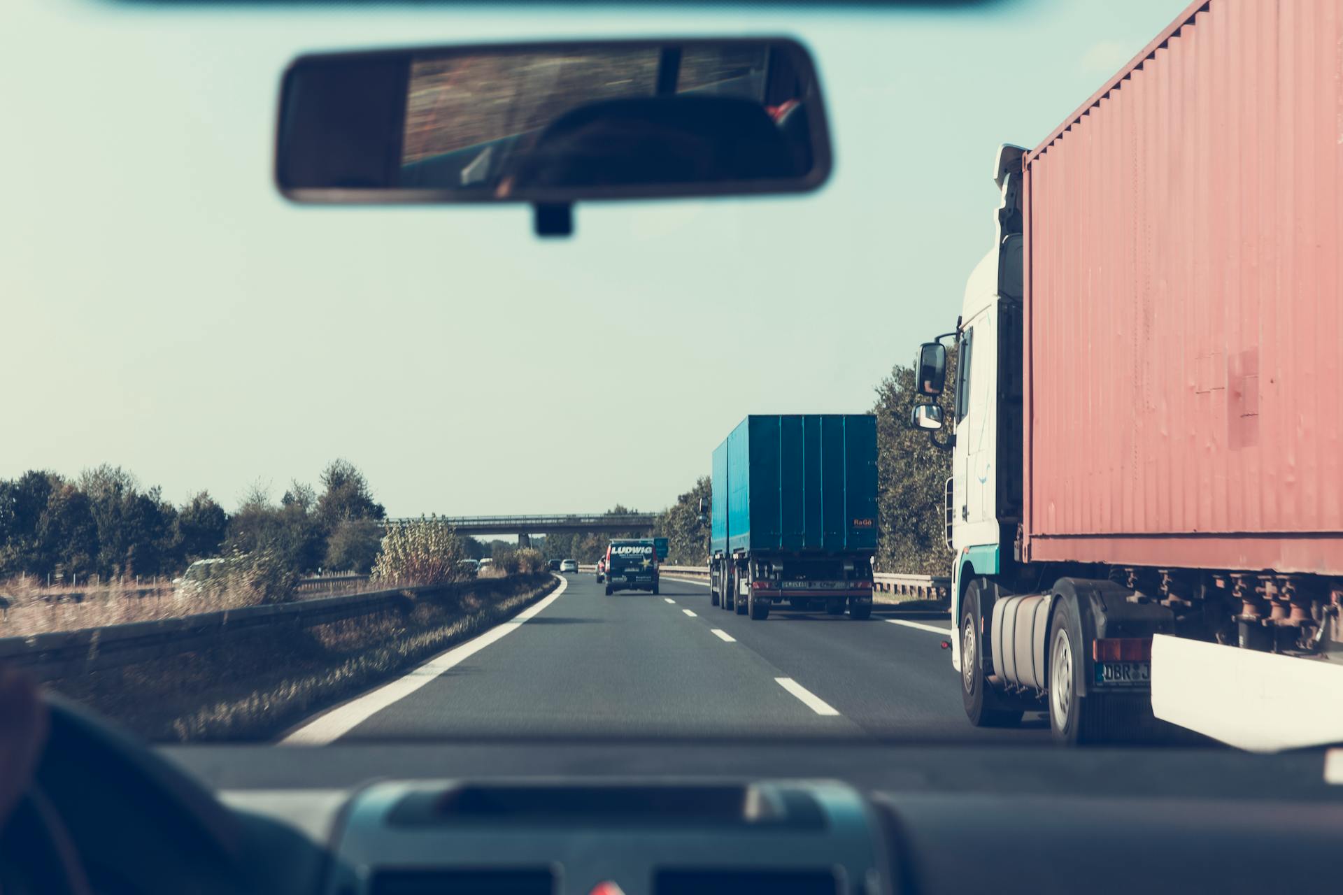 Camions de marchandises bleus et rouges sur une autoroute | Source : Pexels