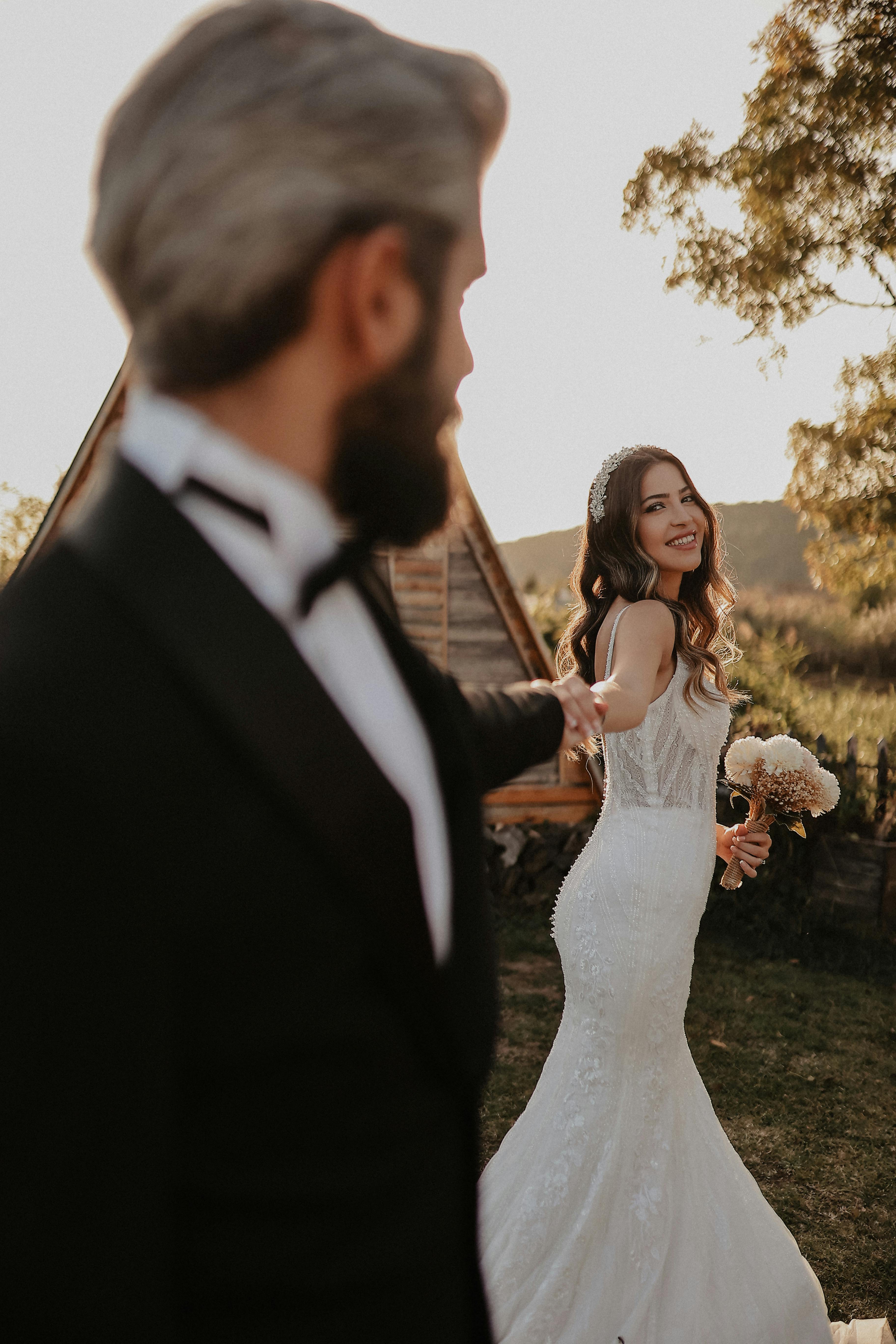 Une mariée et un marié posant dehors au coucher du soleil | Source : Pexels