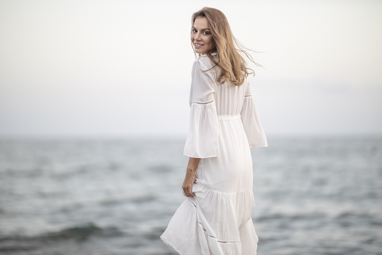 Une femme souriante en robe blanche | Source : Pixabay