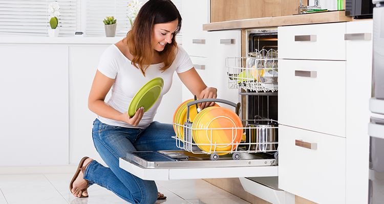 Une Femme qui range sa vaisselle dans le Lave-vaisselle | Photo : Shutterstock