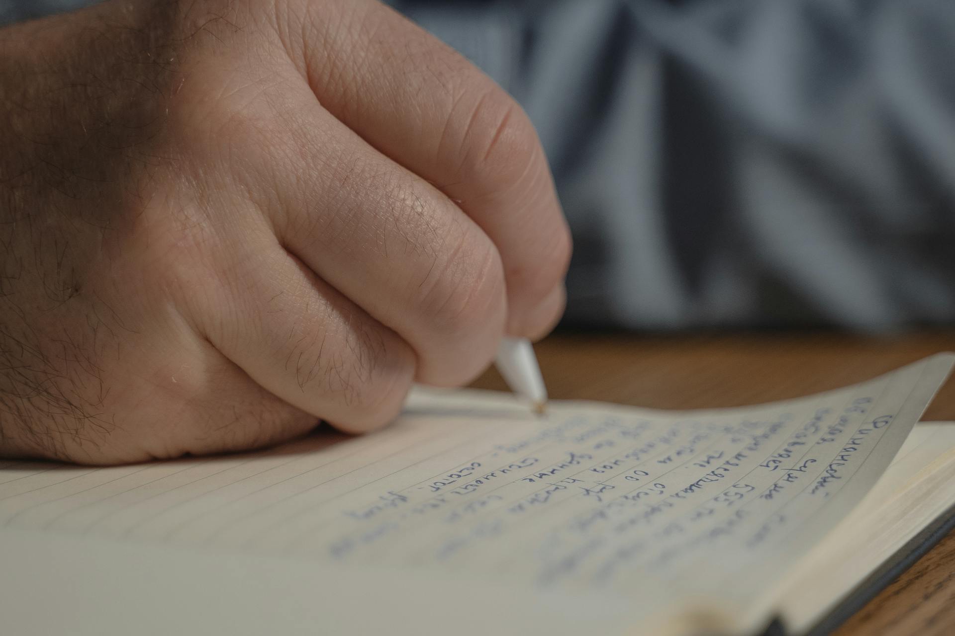 Gros plan d'un homme écrivant dans un journal intime | Source : Pexels