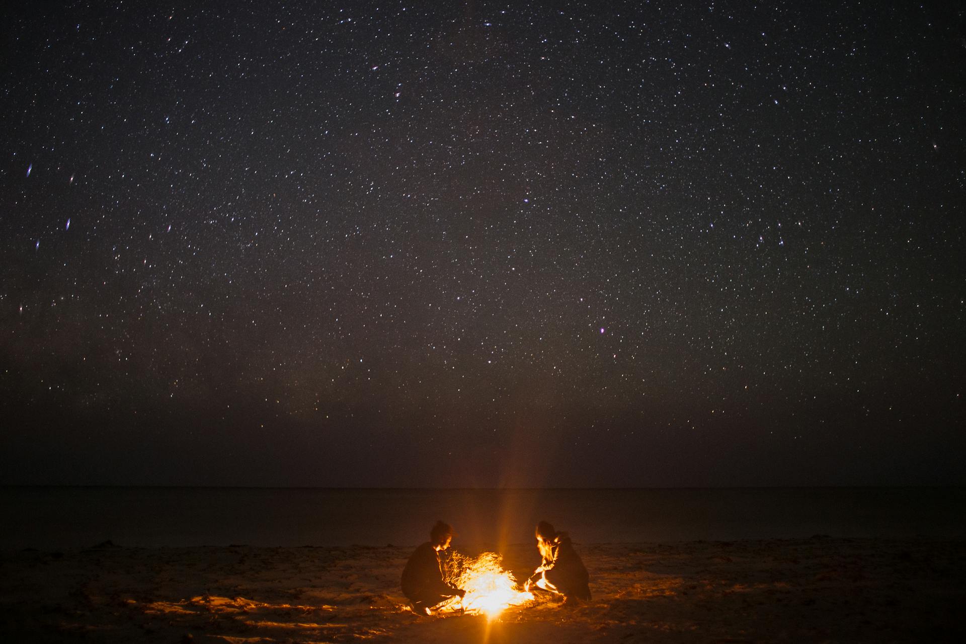 Des gens près d'un feu de joie sur une plage la nuit | Source : Pexels