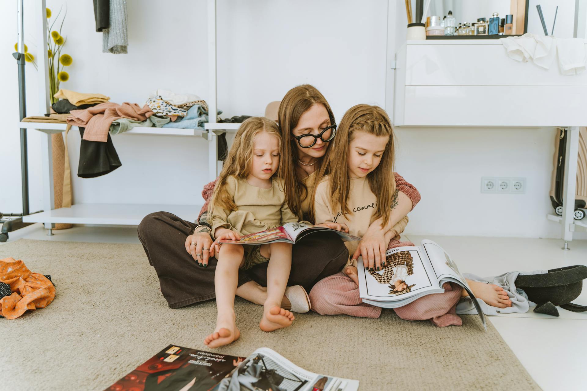 Une femme passe au crible des magazines avec ses petites filles | Source : Pexels