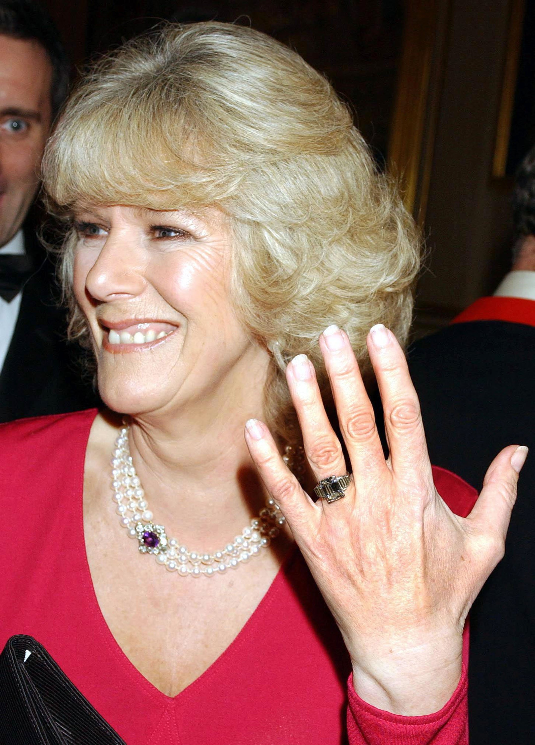Camilla Parker Bowles montre sa bague de fiançailles lorsqu'elle arrive à une fête au château de Windsor après l'annonce de leurs fiançailles le 10 février 2005. | Source : Getty Images  