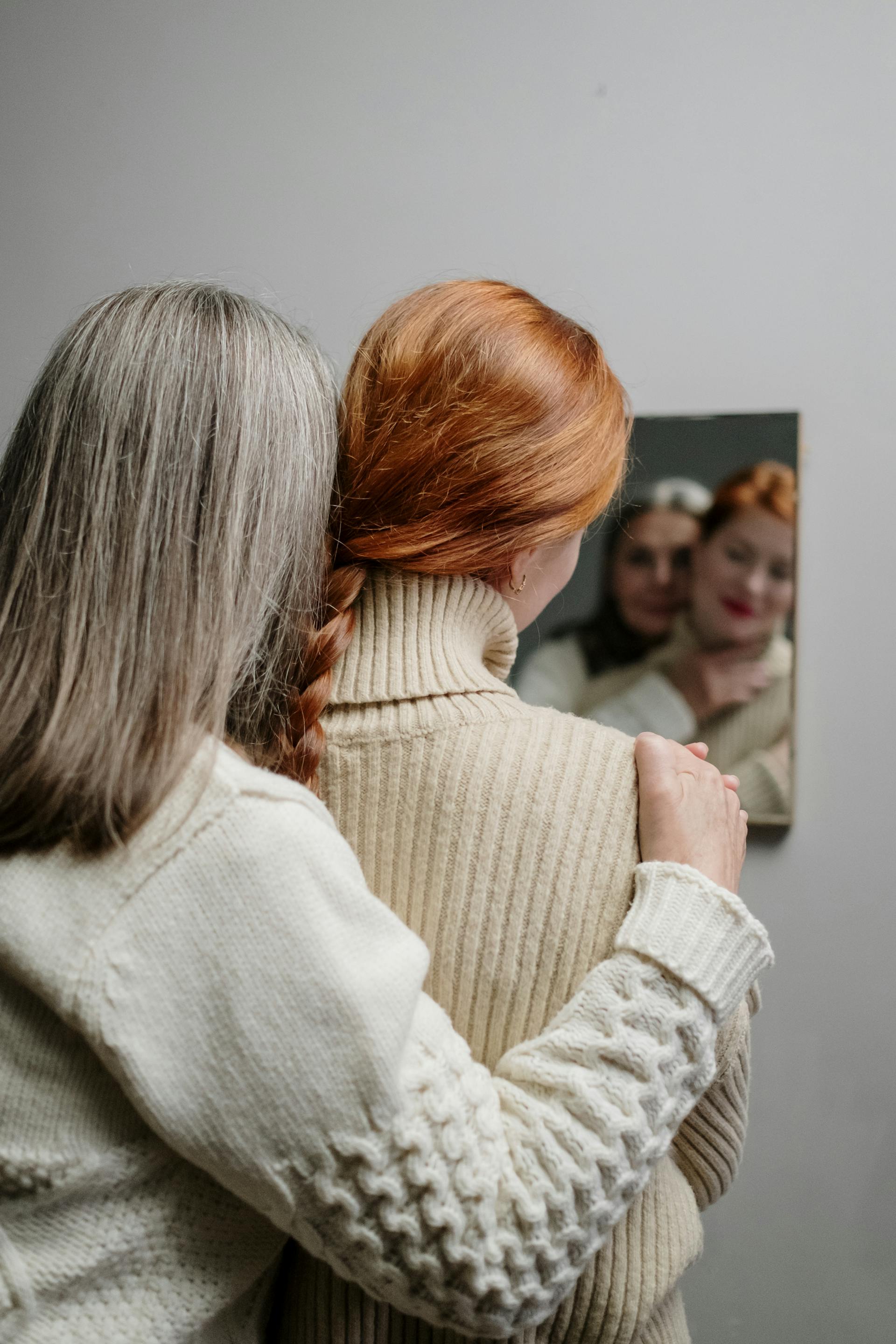 Une mère et sa fille se serrent dans les bras en regardant leurs reflets dans le miroir | Source : Pexels