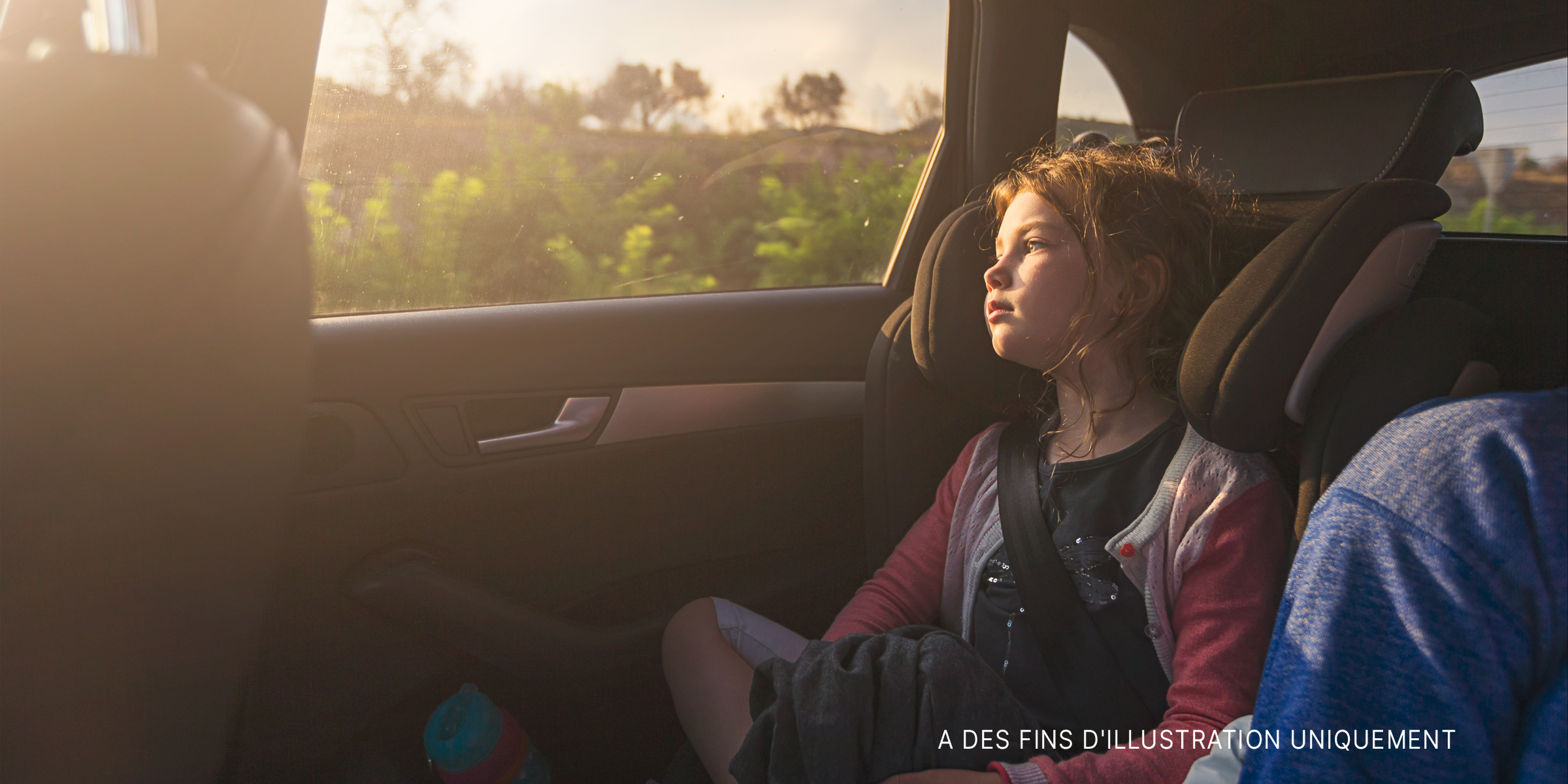 Jeune fille regardant par la fenêtre d'une voiture | Source : Getty Images