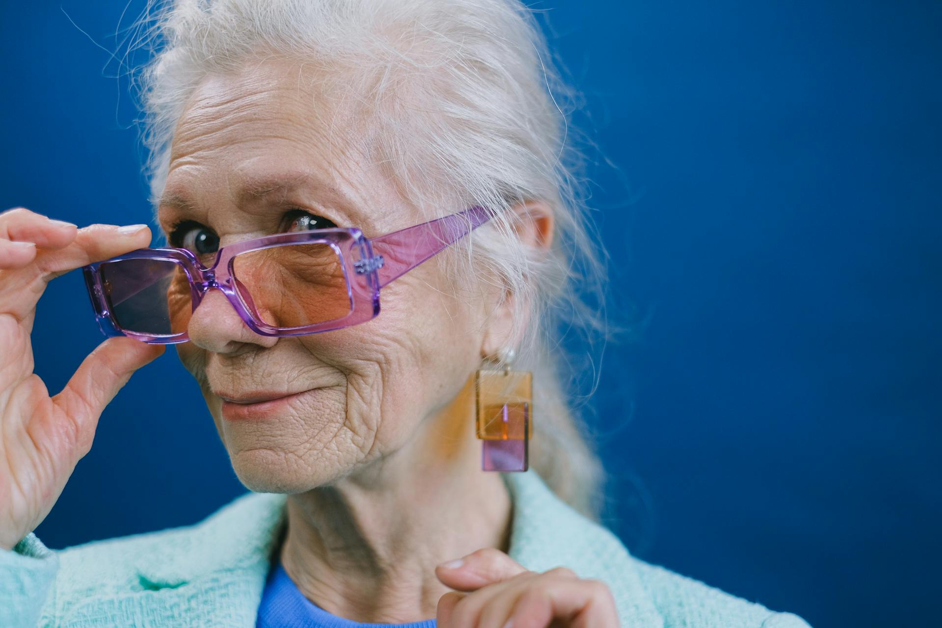 Une femme âgée souriante tenant ses lunettes | Source : Pexels